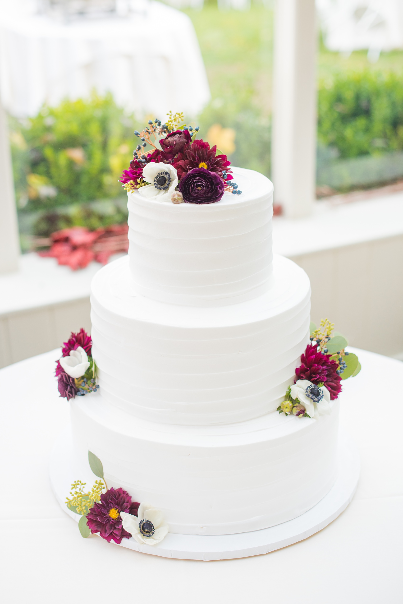 Mikkel Paige Photography photos of a wedding at Crabtree's Kittle House in Chappaqua, New York. Picture of the white buttercream cake decorated with fresh fall flowers.