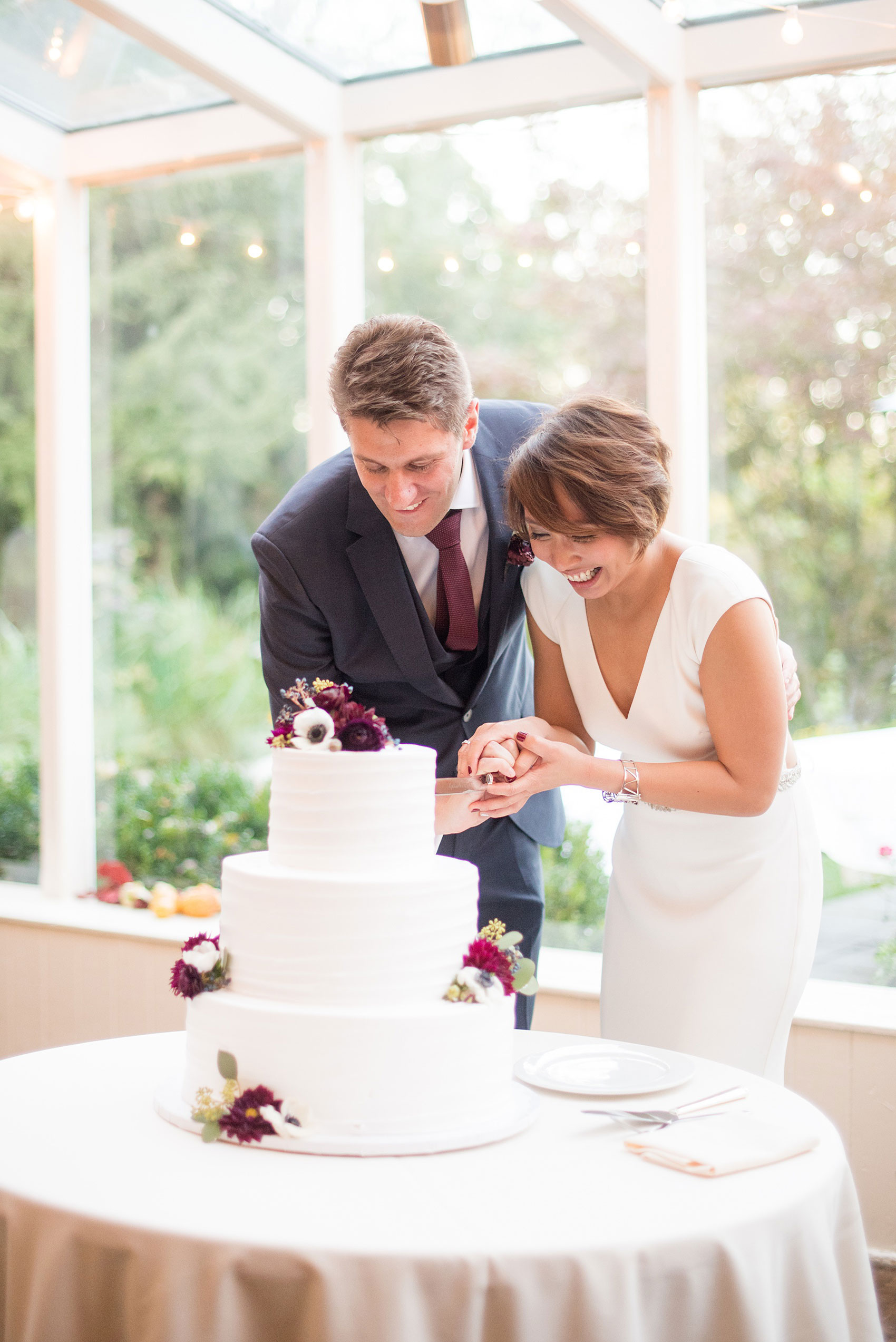 Mikkel Paige Photography photos of a wedding at Crabtree's Kittle House in Chappaqua, New York. Photo of the bride and groom cutting their white buttercream cake.