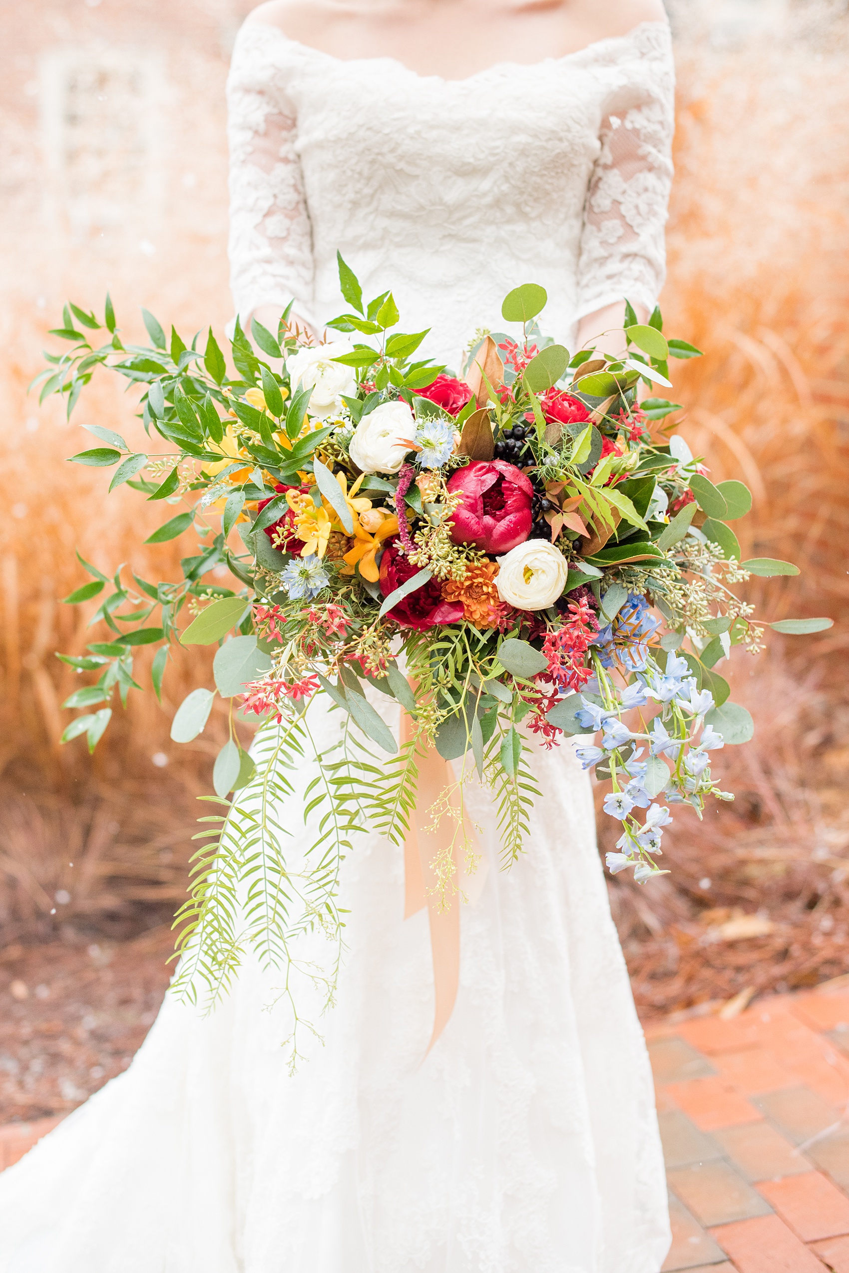 Beautiful wedding photos at The Carolina Inn at Chapel Hill, North Carolina by Mikkel Paige Photography. Detail photo of the bride's bouquet with fall and winter flowers, with burgundy peonies, cascading fern, white ranunculus and orange orchids created by English Garden. Click through to see the rest of this gorgeous winter wedding! #thecarolinainn #snowywedding