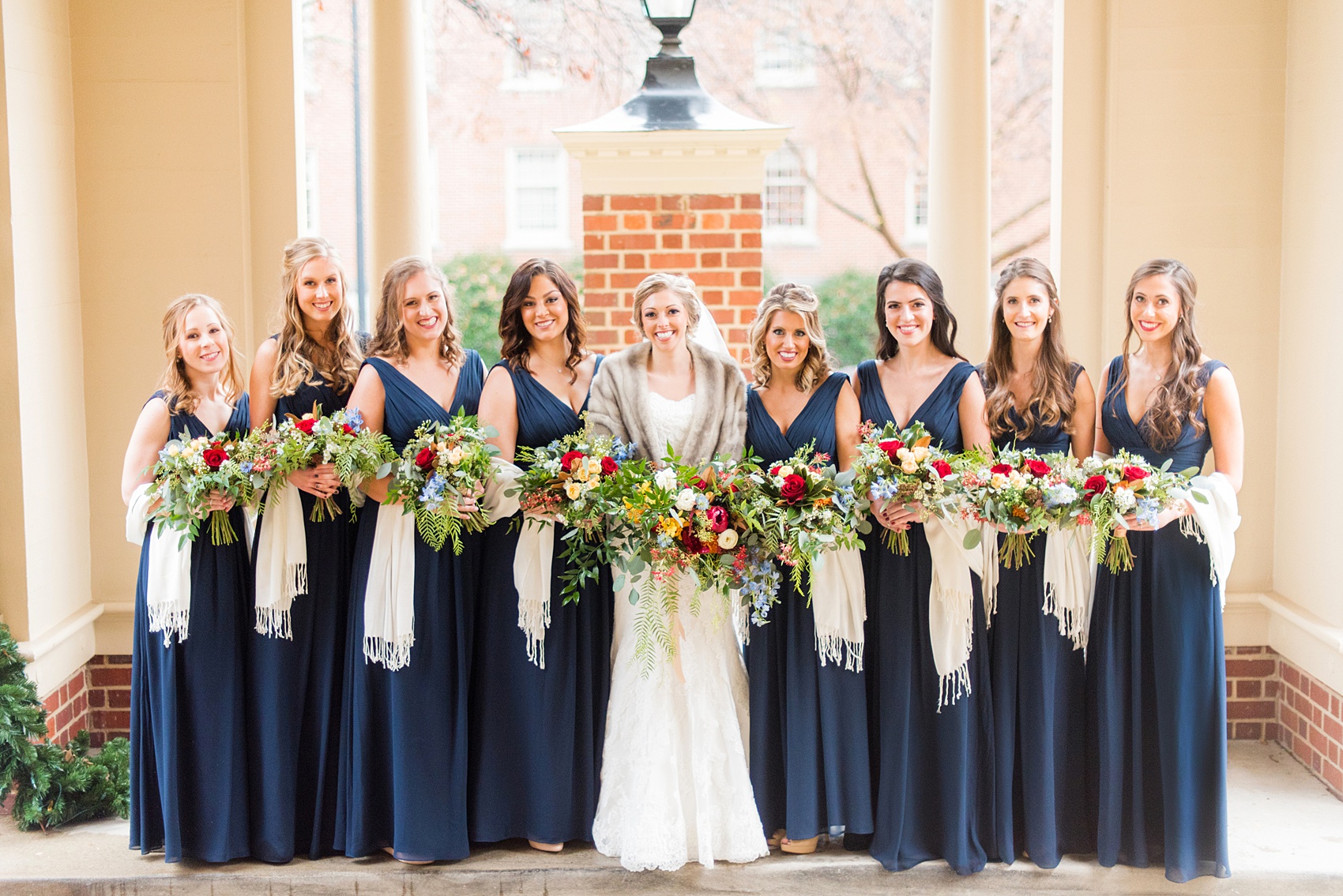 Beautiful wedding photos at The Carolina Inn at Chapel Hill, North Carolina by Mikkel Paige Photography. Photo of the bridal party in navy blue gowns with winter colorful bouquets and white shawls. Click through to see the rest of this gorgeous winter wedding! #thecarolinainn #snowywedding