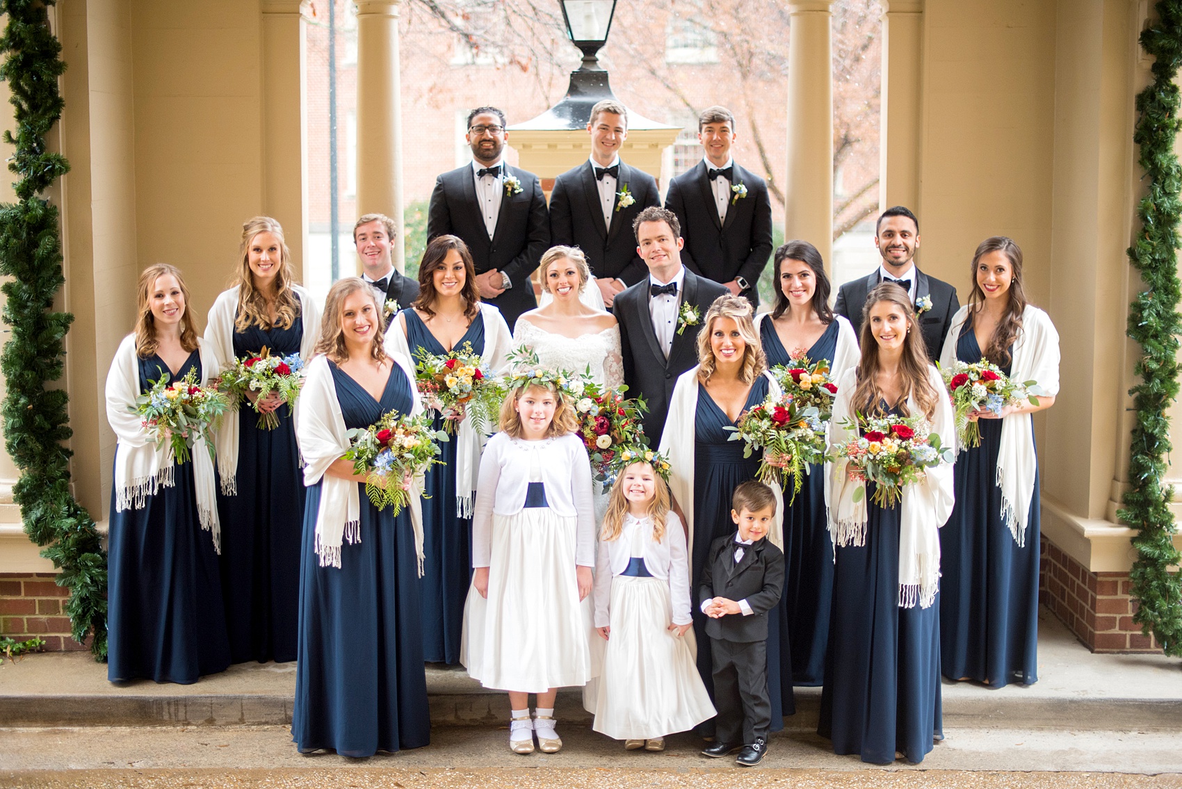 Beautiful wedding photos at The Carolina Inn at Chapel Hill, North Carolina by Mikkel Paige Photography. Photo of the bridesmaids in navy blue gowns with winter colorful bouquets and white shawls and groomsmen in black tuxedos. Click through to see the rest of this gorgeous winter wedding! #thecarolinainn #snowywedding