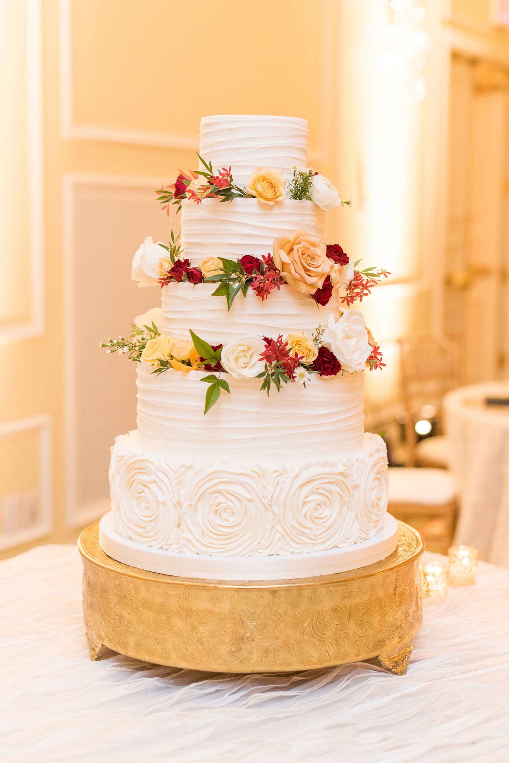 Beautiful wedding photos at The Carolina Inn at Chapel Hill, North Carolina by Mikkel Paige Photography. Picture of the white buttercream cake by Ashley Cakes, NC decorated with white, yellow and red roses and greenery. Click through to see the rest of this gorgeous winter wedding! #thecarolinainn #snowywedding