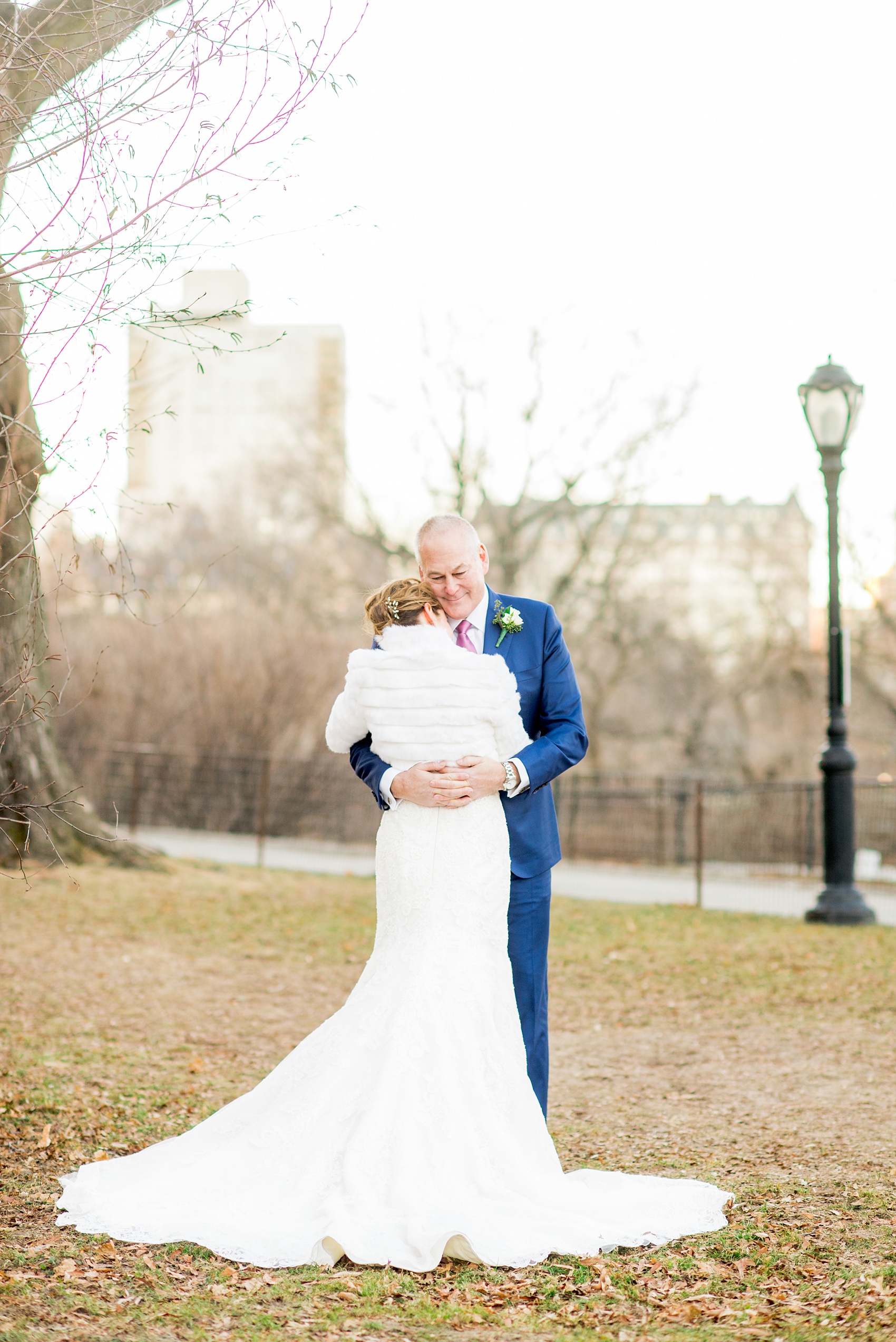 Photos by Mikkel Paige Photography of a Central Park Wedding ceremony and reception at the Loeb Boathouse venue with a romantic winter theme. The bride and groom took pictures around the park in his custom navy blue suit and her lace gown with short white fur coat. Click through for more images from their day! #CentralParkWedding