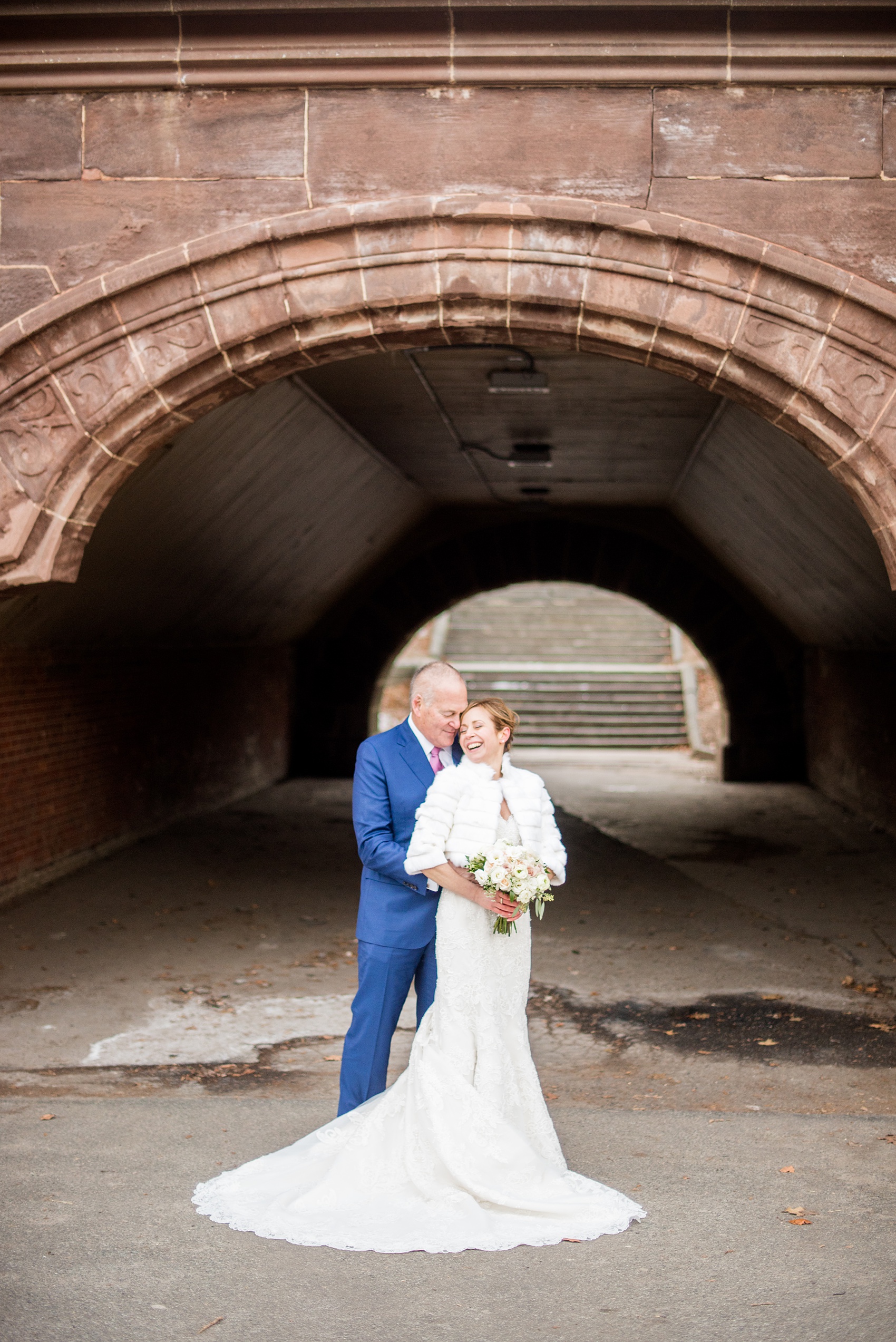 Photos by Mikkel Paige Photography of a Central Park Wedding ceremony and reception at the Loeb Boathouse venue with a romantic winter theme. The bride and groom took pictures around the park in his custom navy blue suit and her lace gown with short white fur coat. Click through for more images from their day! #CentralParkWedding