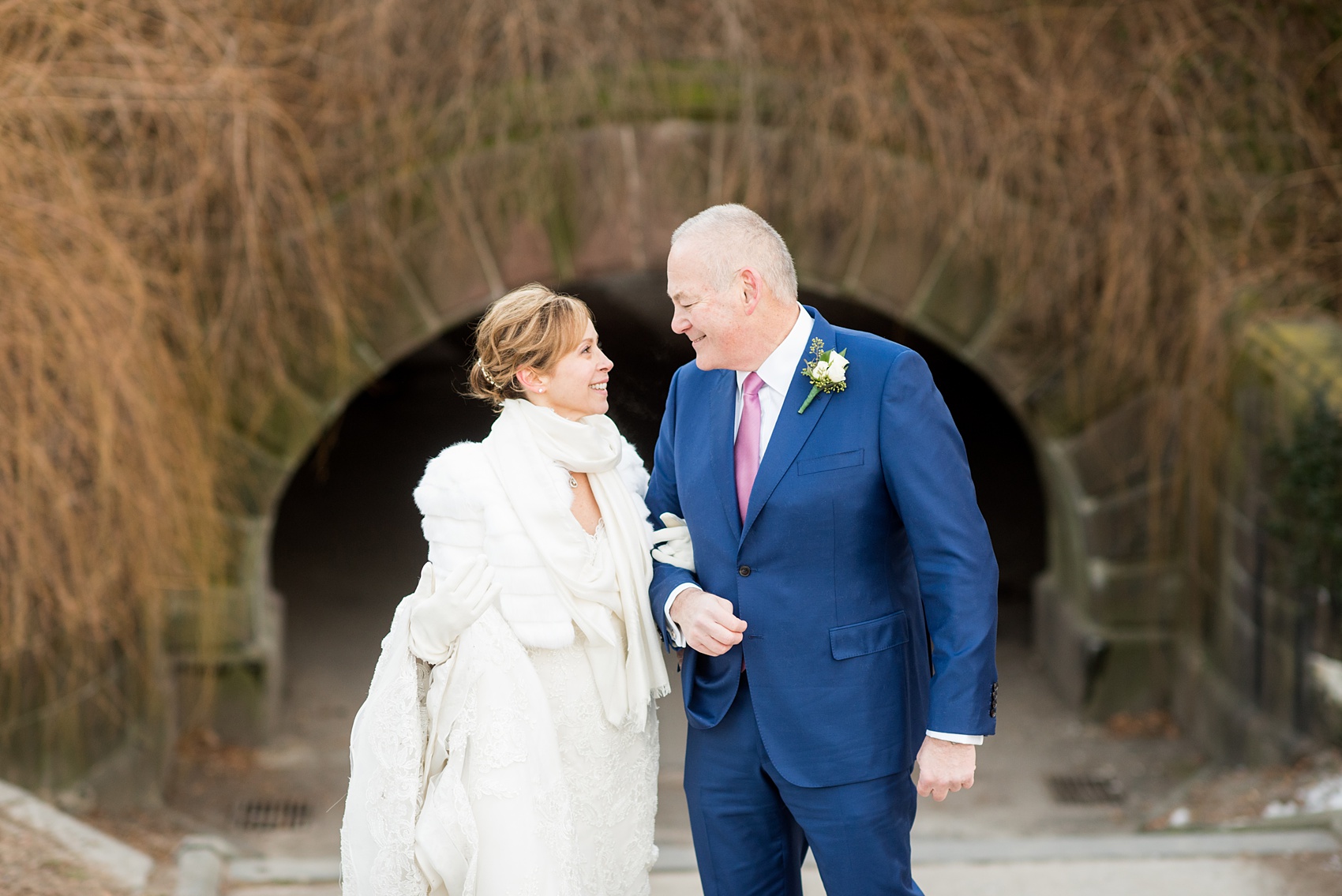 Photos by Mikkel Paige Photography of a Central Park Wedding ceremony and reception at the Loeb Boathouse venue with a romantic winter theme. The bride and groom took pictures around the park in his custom navy blue suit and her lace gown with short white fur coat. Click through for more images from their day! #CentralParkWedding