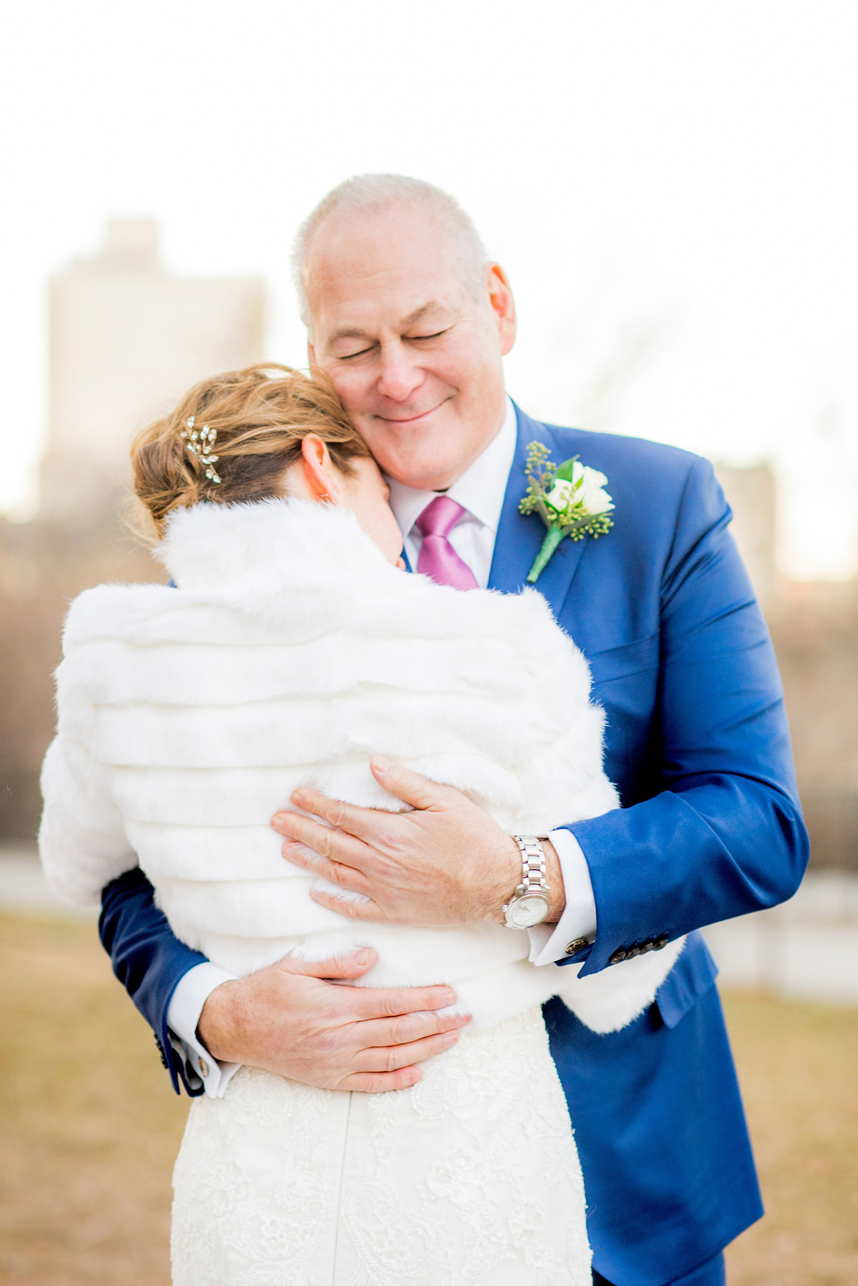 Photos by Mikkel Paige Photography of a Central Park Wedding ceremony and reception at the Loeb Boathouse venue with a romantic winter theme. The bride and groom took pictures around the park in his custom navy blue suit and her lace gown with short white fur coat. Click through for more images from their day! #CentralParkWedding