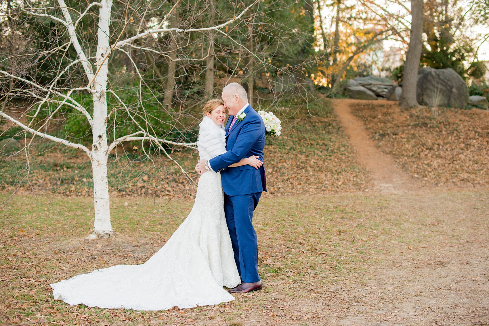 Photos by Mikkel Paige Photography of a Central Park Wedding ceremony and reception at the Loeb Boathouse venue with a romantic winter theme. The bride and groom took pictures around the park in his custom navy blue suit and her lace gown with short white fur coat. Click through for more images from their day! #CentralParkWedding