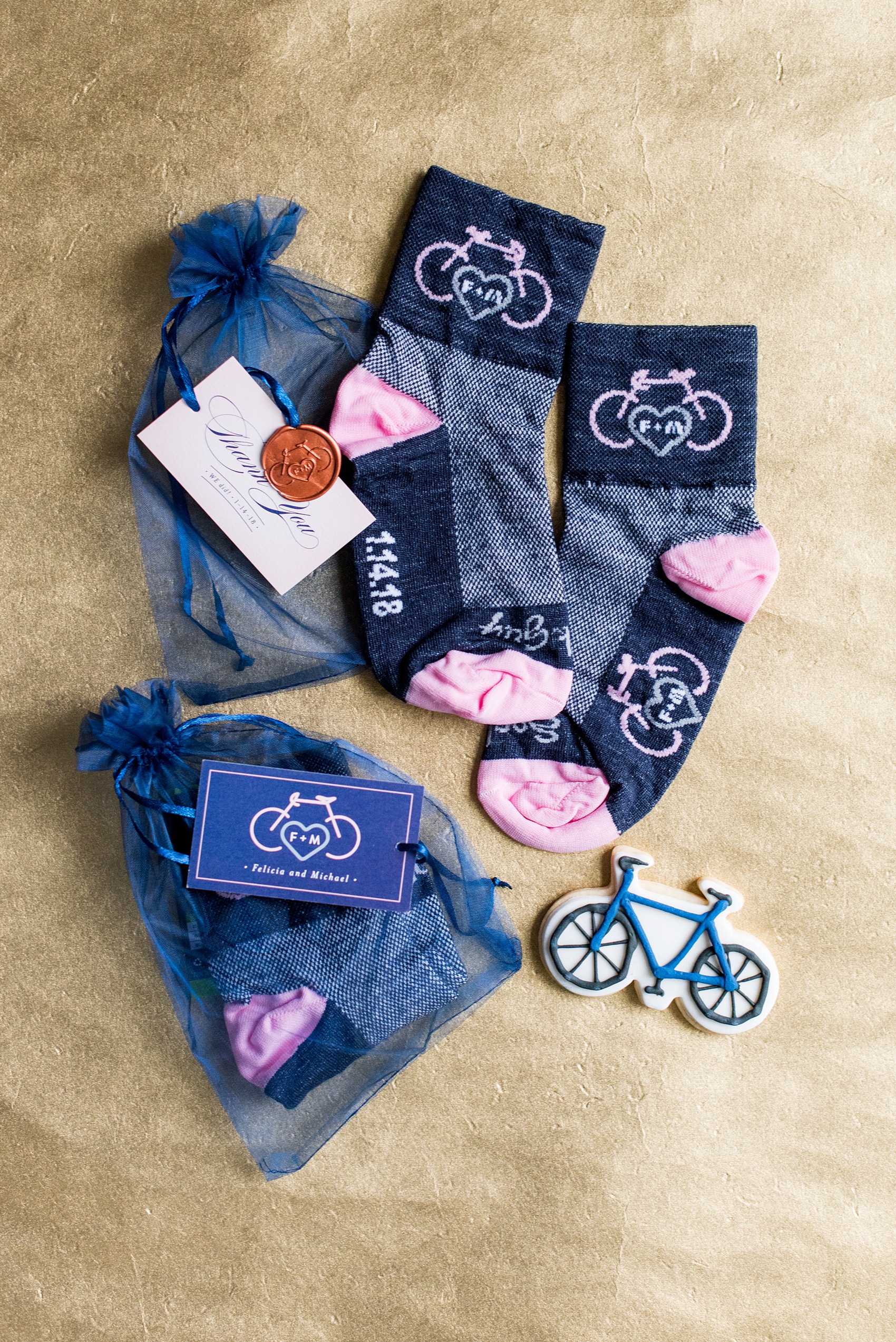 Photos by Mikkel Paige Photography of a Central Park Wedding ceremony and reception at the Loeb Boathouse venue with a romantic winter theme. A detail picture of the couple's guest favors: custom cycling socks with their winter, January wedding date, and bicycle sugar cookies. Click through for more images from their day! #CentralParkWedding