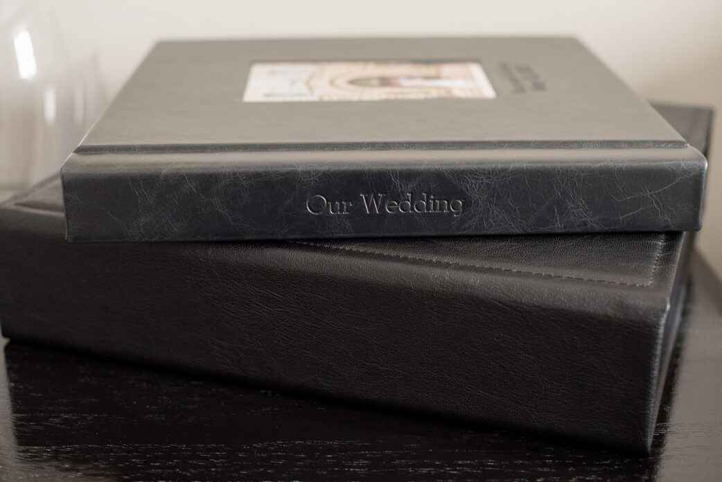 Images of a black calf leather fine art wedding album from Mikkel Paige Photography, a Raleigh, NC photographer. Photo shows spine debossing text.