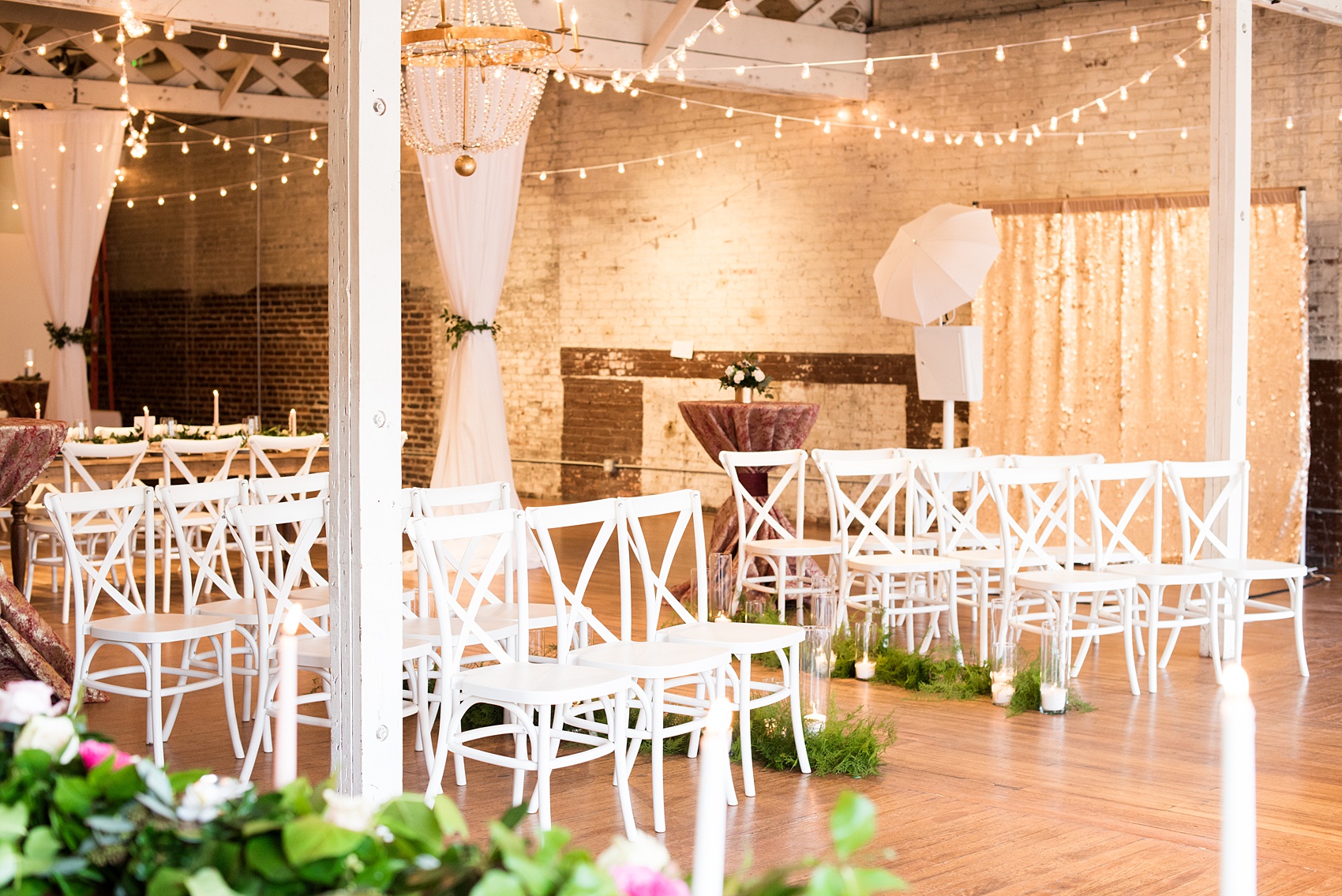 Photos from a wedding in downtown Raleigh, NC by Mikkel Paige Photography. The Stockroom at 230 and The Glass Box on historic Fayetteville Street served as the venue for this romantic inspiration shoot. The indoor ceremony was accented by white chairs, greenery on the aisle lit by candlelight and various drapery.