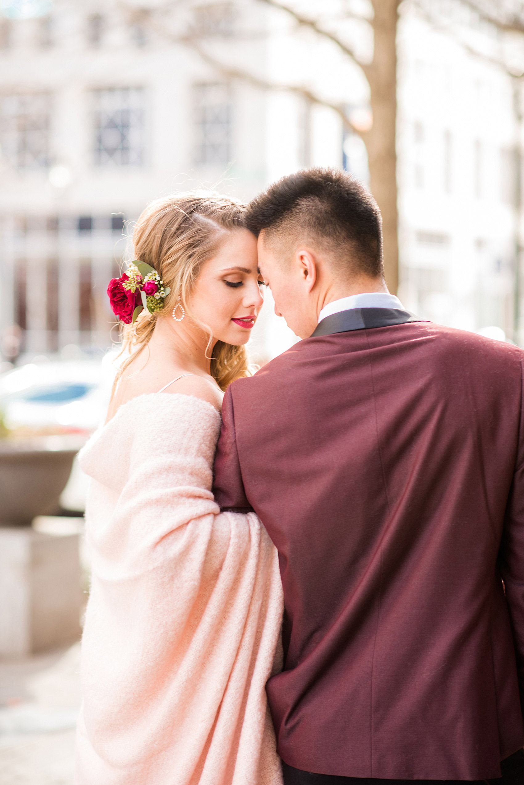 Photos from a wedding in downtown Raleigh, NC by Mikkel Paige Photography. The bride and groom snuggle under a pink blanket, with the groom in a maroon tuxedo, on historic Fayetteville Street, as they walked to their historic venue, The Stockroom at 230.