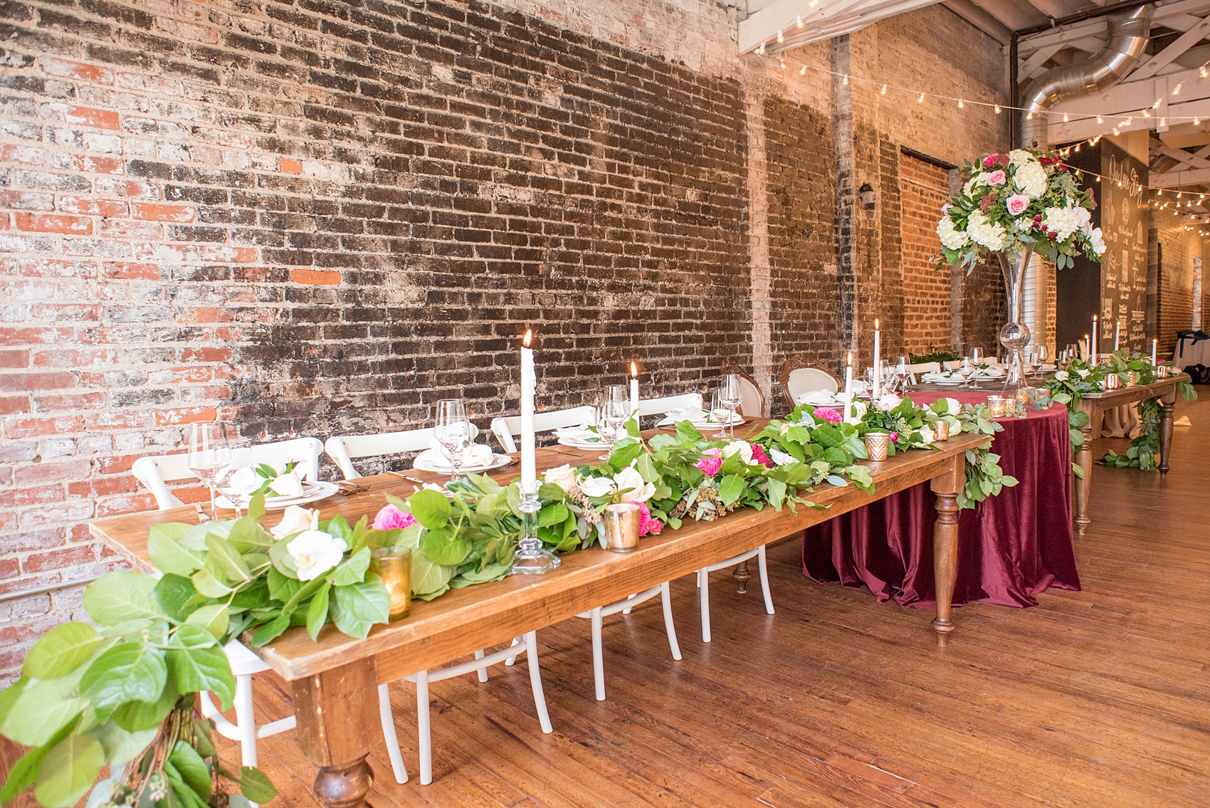 Photos from a wedding in downtown Raleigh, NC by Mikkel Paige Photography. The reception was in historic Fayetteville Street's The Stockroom at 230. The farm tables were lined with greenery garland and colorful flowers for a winter wedding.