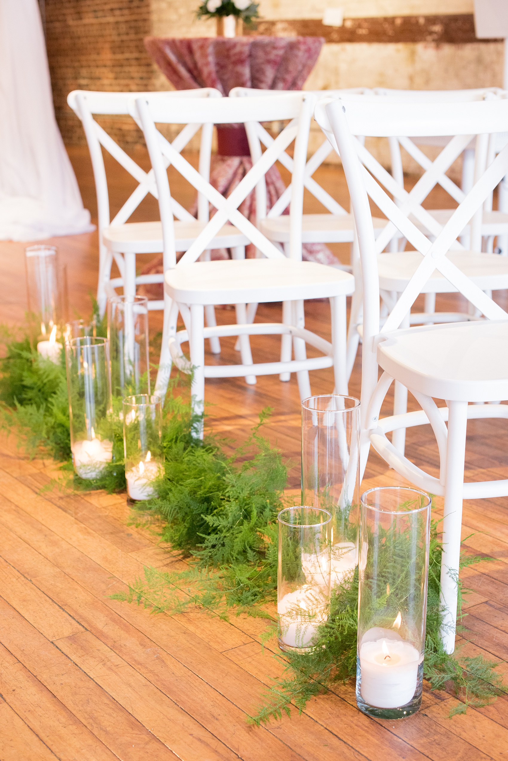 Photos from a wedding in downtown Raleigh, NC by Mikkel Paige Photography. The ceremony was held inside the historic venue, The Stockroom at 230, with white chairs and greenery lined aisles drenched with candlelight.