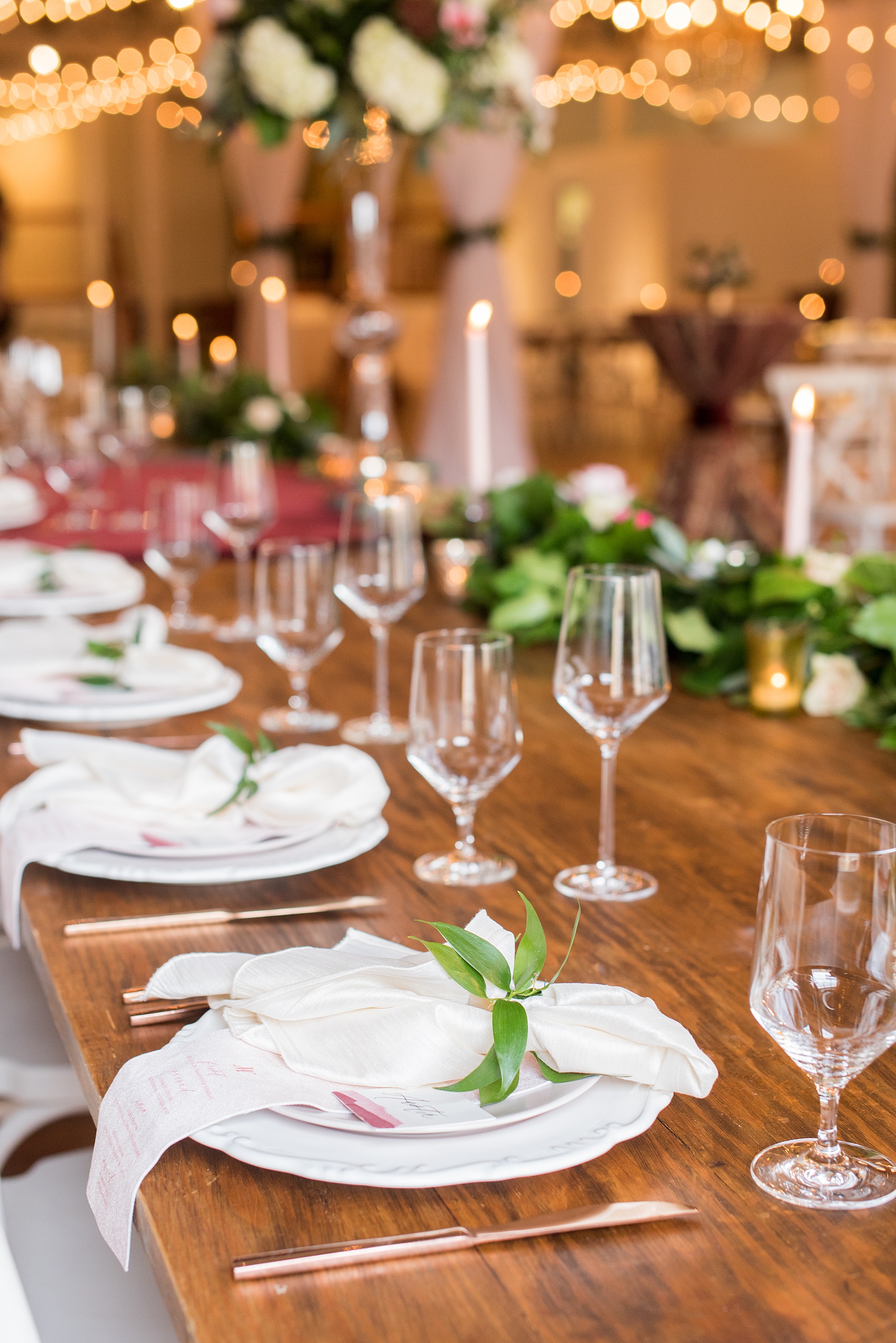 Photos from a wedding in downtown Raleigh, NC by Mikkel Paige Photography. The reception was held inside the historic venue, The Stockroom at 230. White and pink place settings were on top of natural wood farm tables with green garland and colorful flowers. 