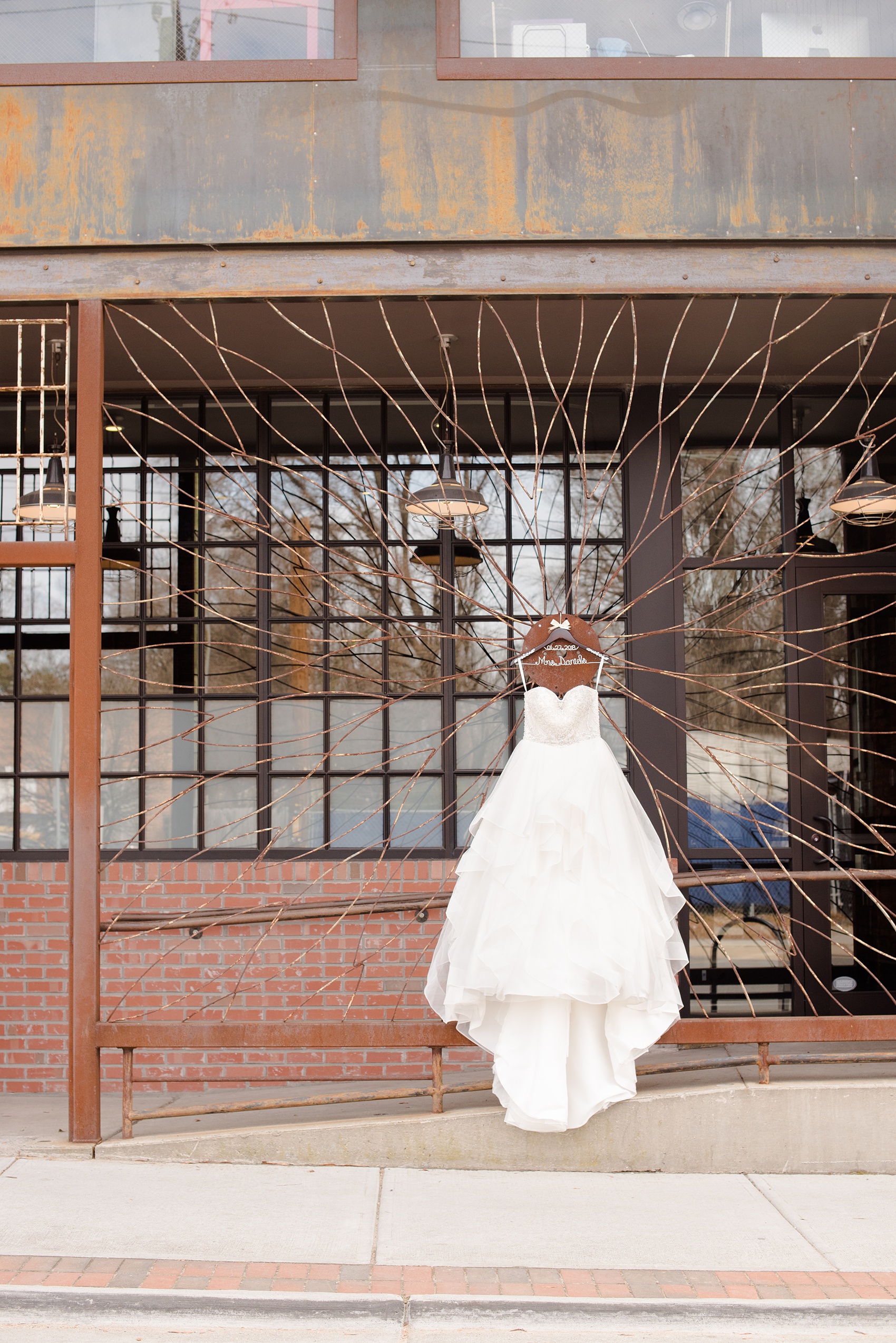 Durham wedding photos at The Cookery by Mikkel Paige Photography in North Carolina. The bride's white gown hung on the front iron gate of the venue in this detail picture.