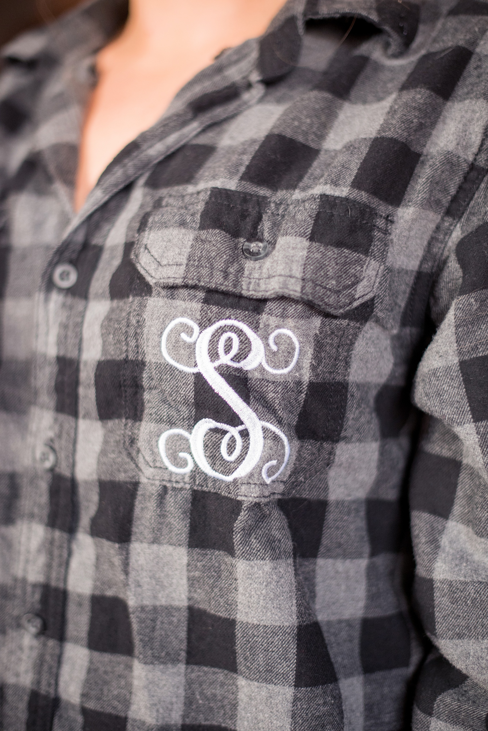 Durham wedding photos at The Cookery by Mikkel Paige Photography in North Carolina. The brought gifted her bridesmaids monogrammed button-down plaid shirts with their first initial on the pocket, as shown in this detail picture.