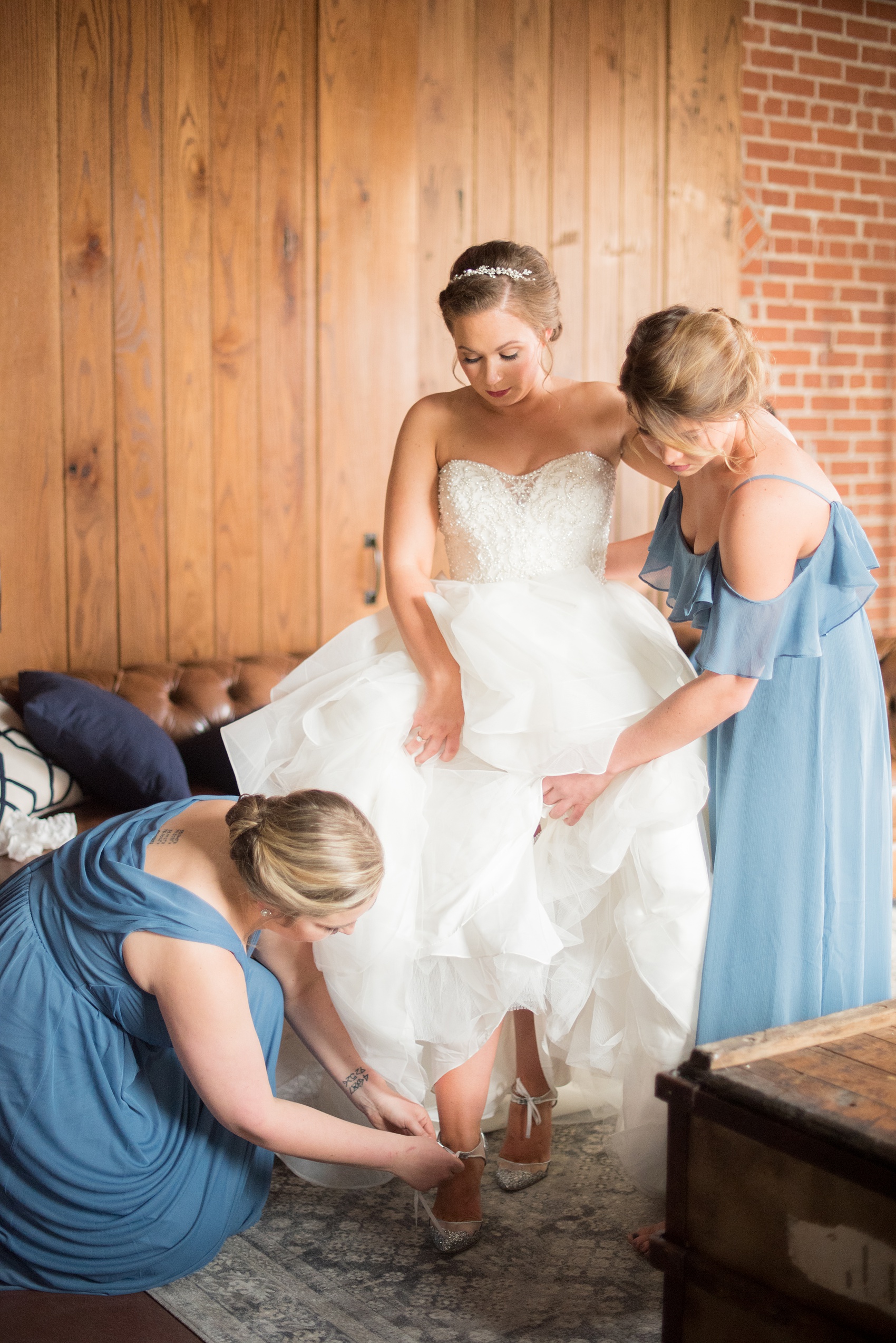 Durham wedding photos at The Cookery by Mikkel Paige Photography in North Carolina. The bridesmaids helped the bride put on her white mesh and silver glitter wedding day shoes.