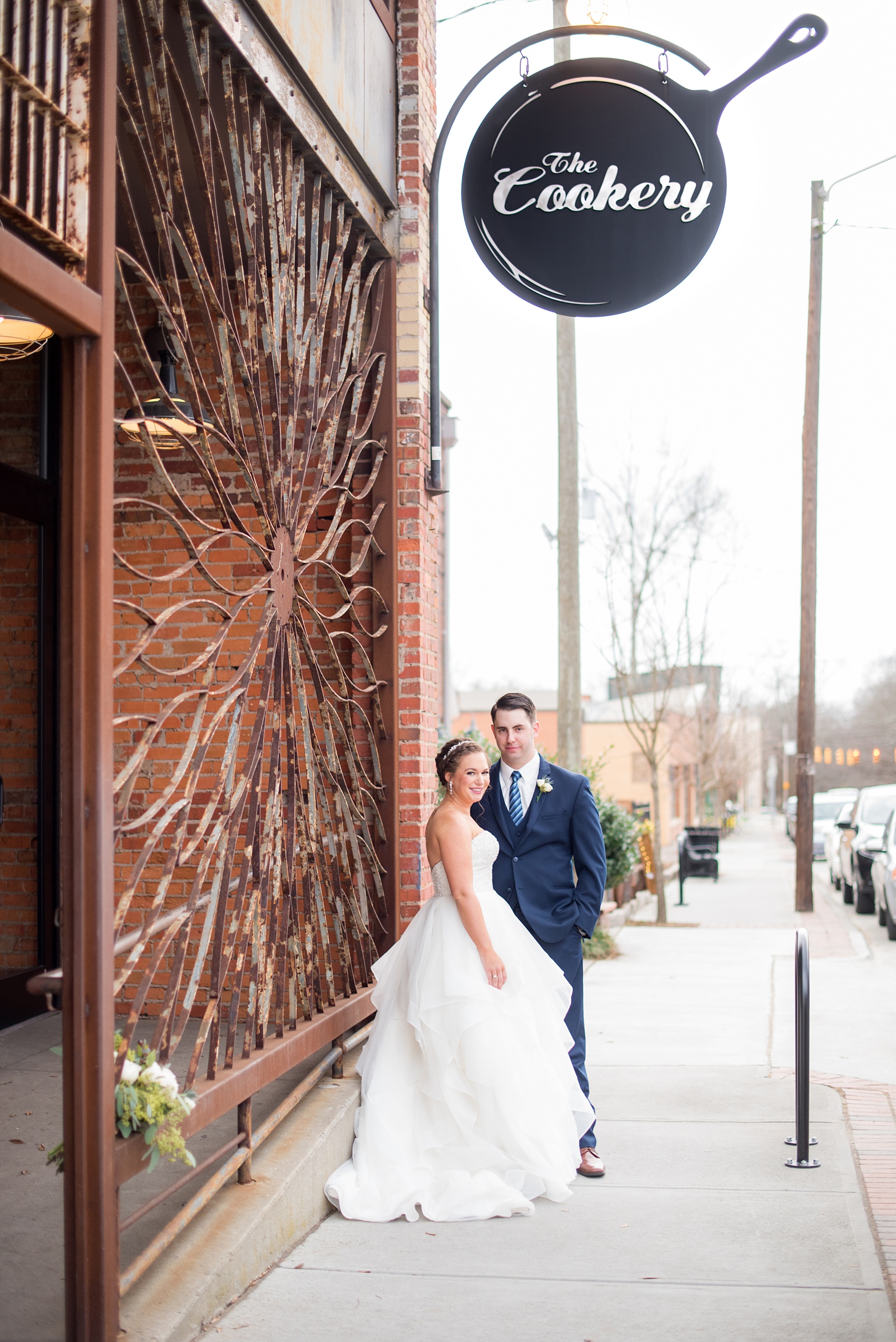 Durham wedding photos at The Cookery with the bride and groom by the rusted exterior stylized sign by Mikkel Paige Photography in North Carolina.