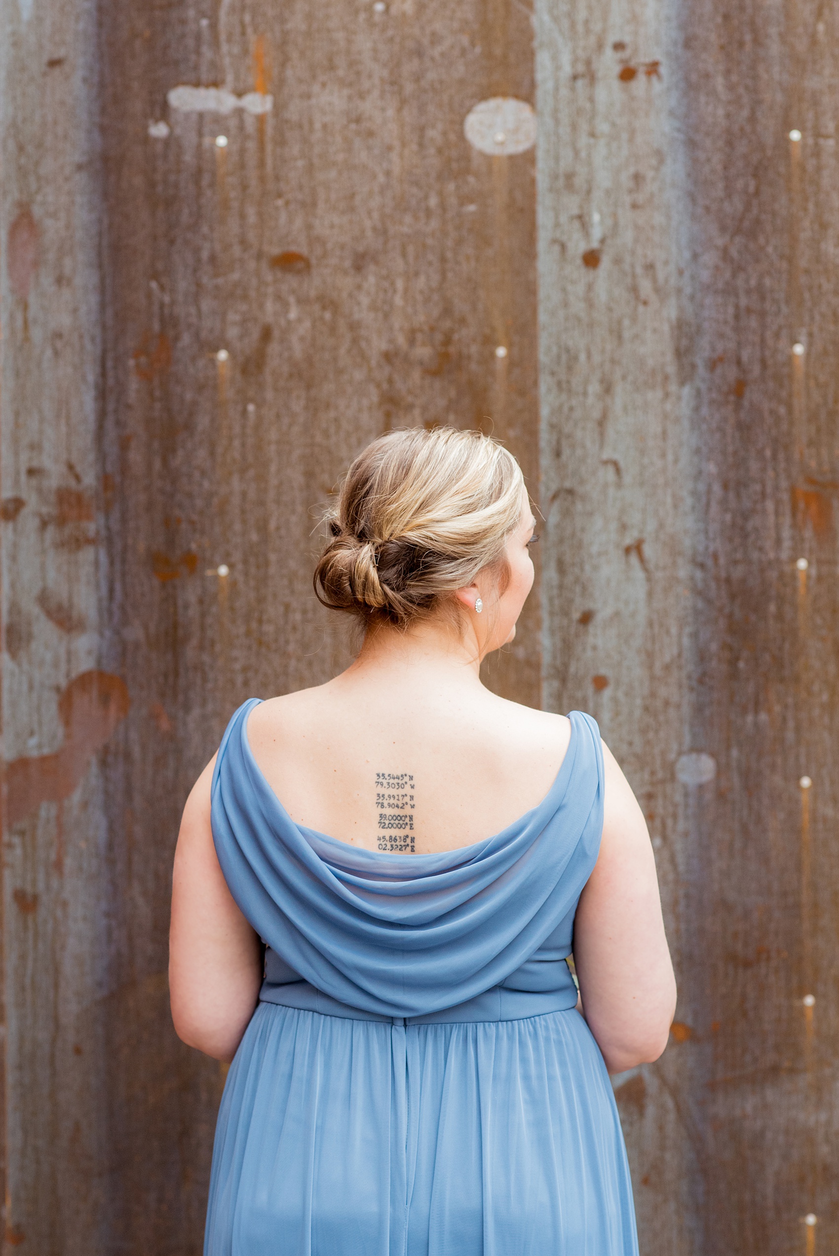 Durham wedding photos at The Cookery by Mikkel Paige Photography in North Carolina. The bridal party wore dusty cornflower blue dresses and one of the bridesmaids took a picture in front of a rustic, urban wall at the venue.