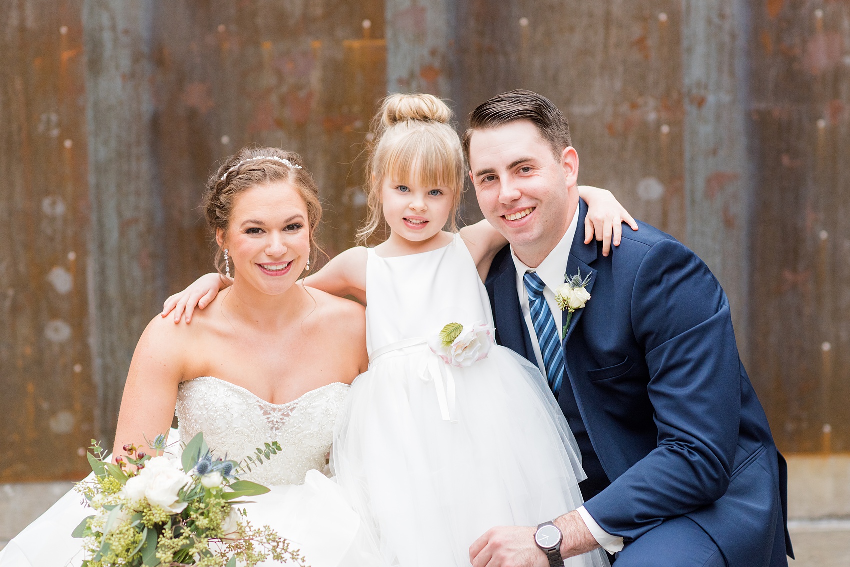 Durham wedding photos at The Cookery by Mikkel Paige Photography in North Carolina. The bride and groom posed for a picture with the flower girl.