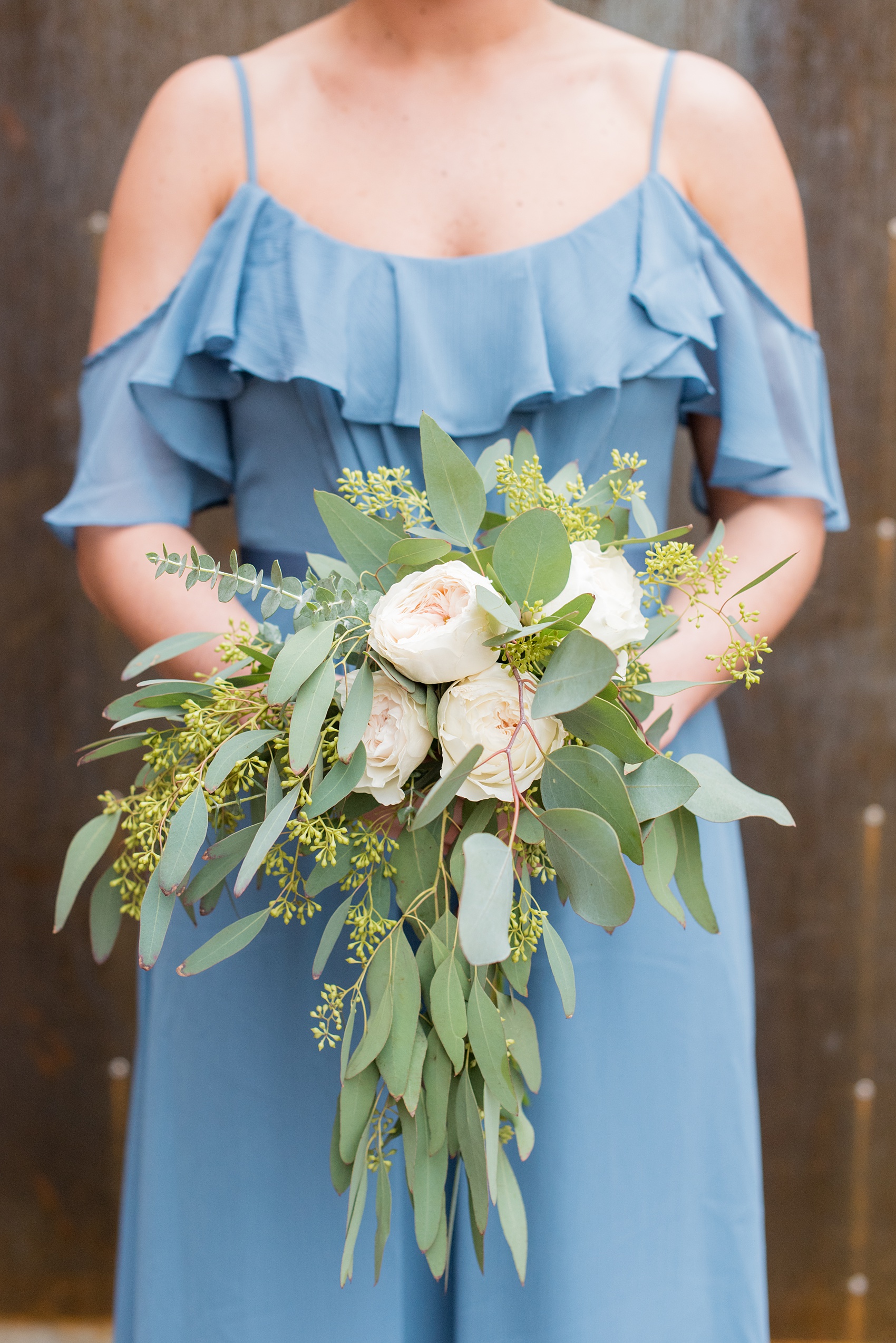 Durham wedding photos at The Cookery by Mikkel Paige Photography in North Carolina. The bridal party wore dusty cornflower blue dresses. Each gown was different and they all held a bouquet of roses and eucalyptus.