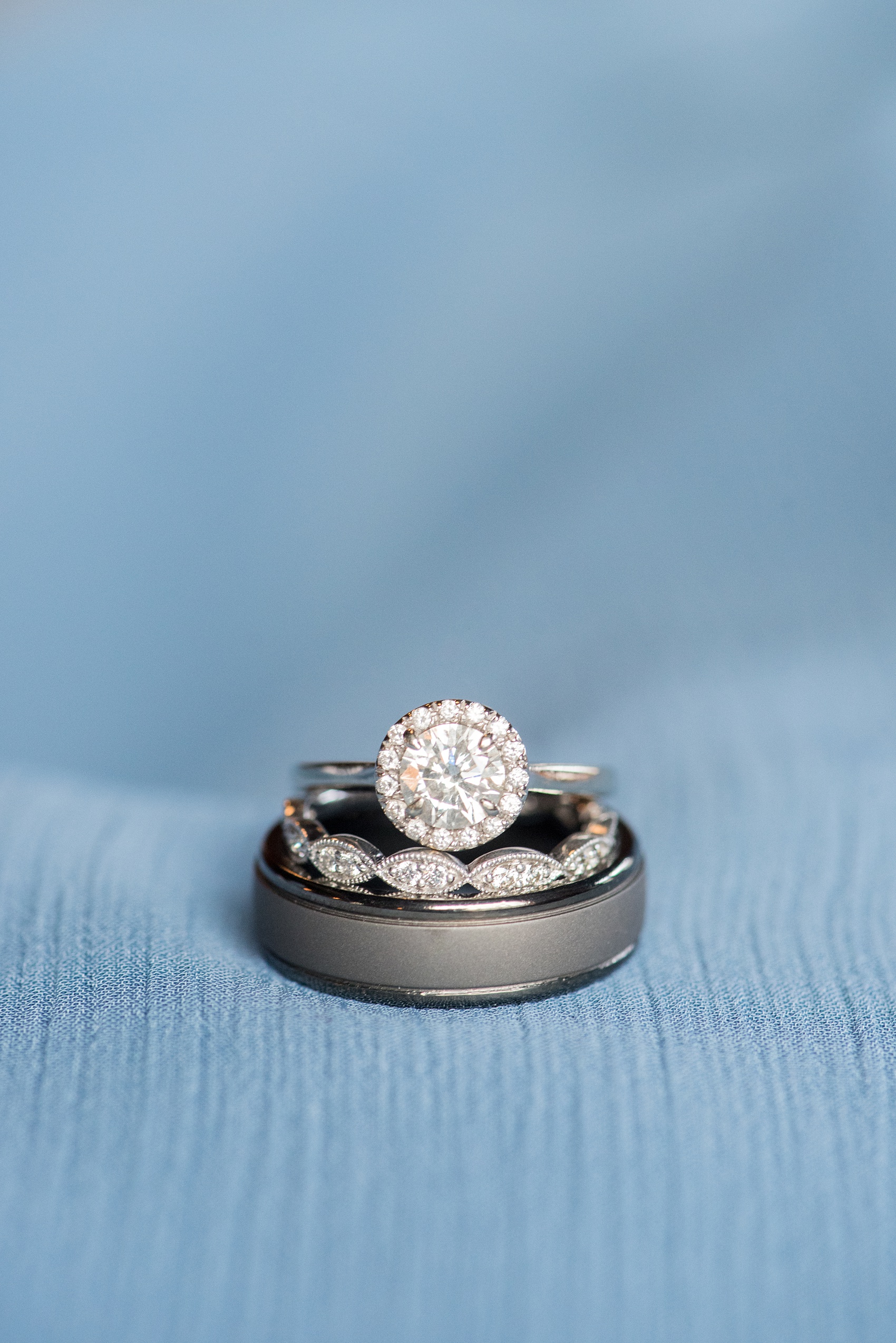 Durham wedding photos at The Cookery by Mikkel Paige Photography in North Carolina. This detail picture shows the bride's round halo diamond engagement ring, marquee wedding band and groom's gunmetal ring.