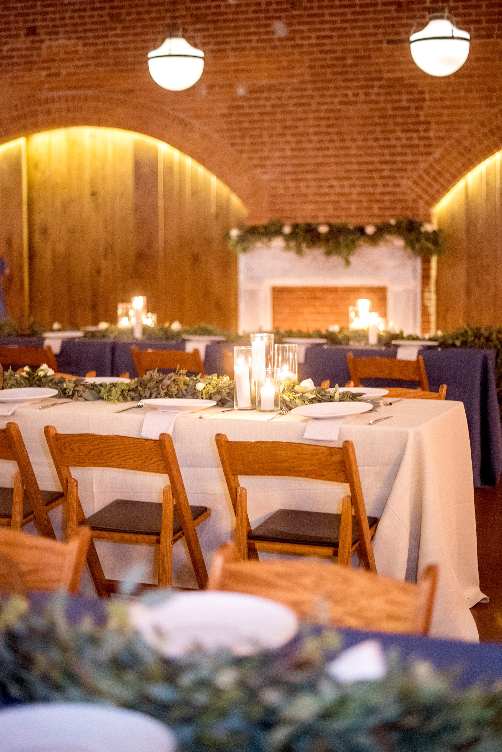 Indoor reception Durham wedding photos at The Cookery by Mikkel Paige Photography in North Carolina. Candlelight and green eucalyptus garland line the rectangular dinner tables.