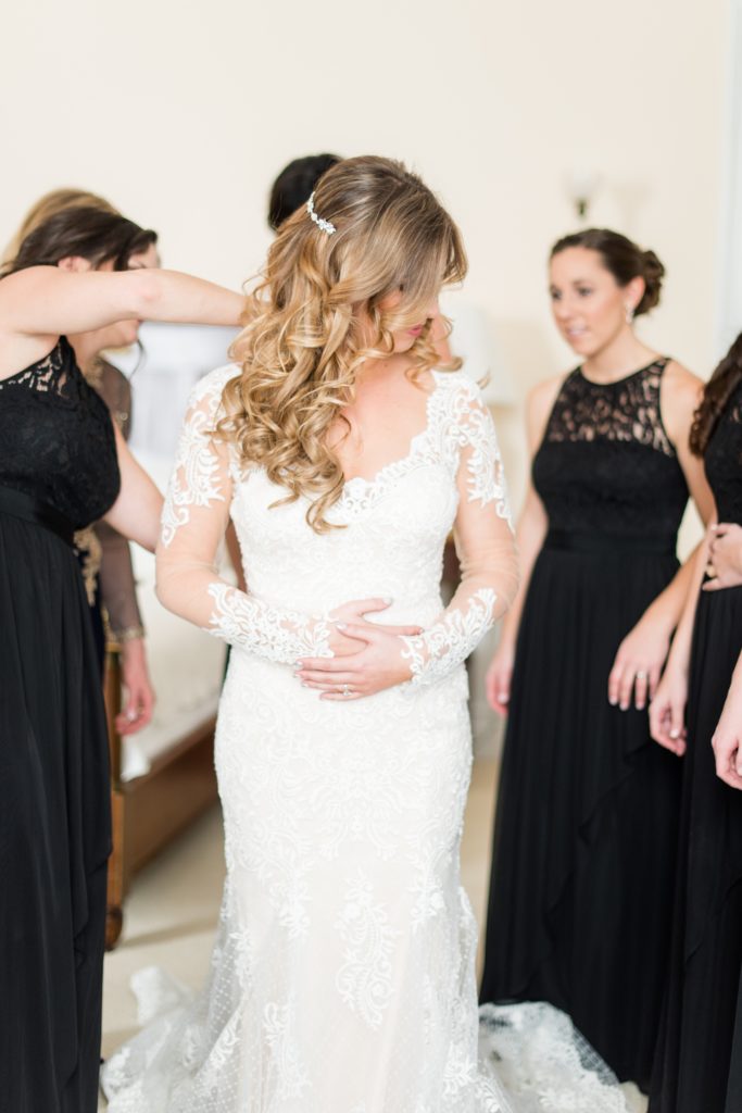 Wedding photos at Sleepy Hollow Country Club for a winter reception in January by Mikkel Paige Photography. The mother of the bride helped her daughter close the buttons of her lace dress on her winter wedding day.