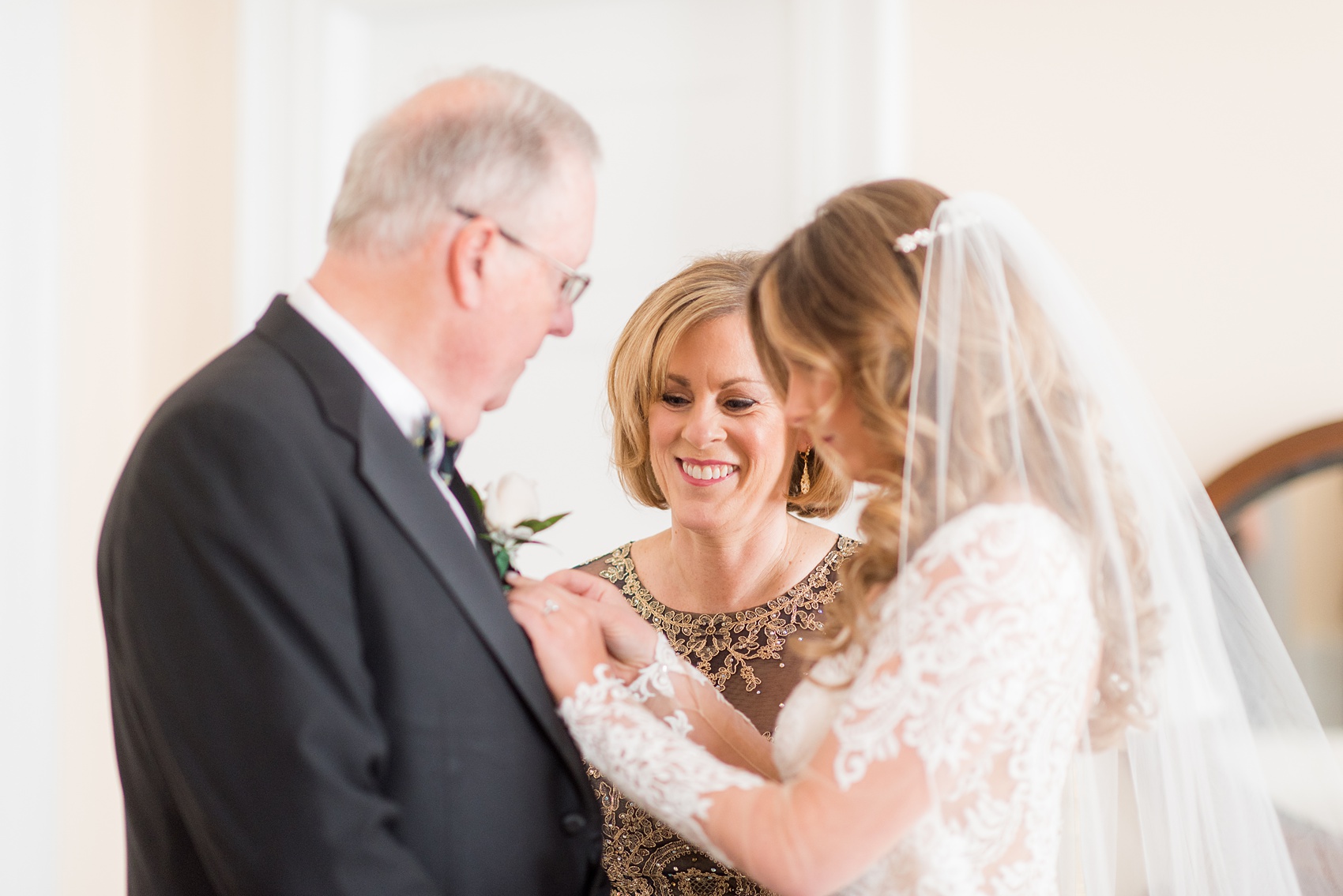 Wedding photos at Sleepy Hollow Country Club for a winter reception in January by Mikkel Paige Photography. A picture of the bride helping pin on her father's boutonniere.