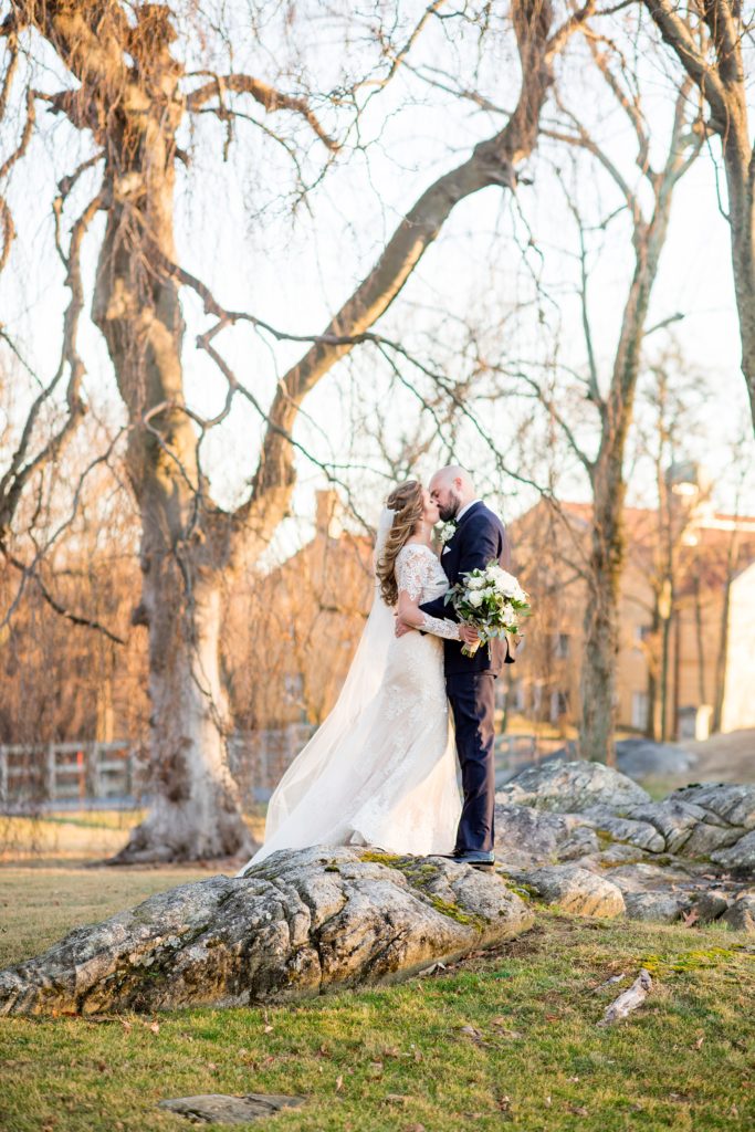 Wedding photos at Sleepy Hollow Country Club for a winter reception in January by Mikkel Paige Photography. A picture of the bride and groom kissing on rustic rocks during their winter wedding in New York.