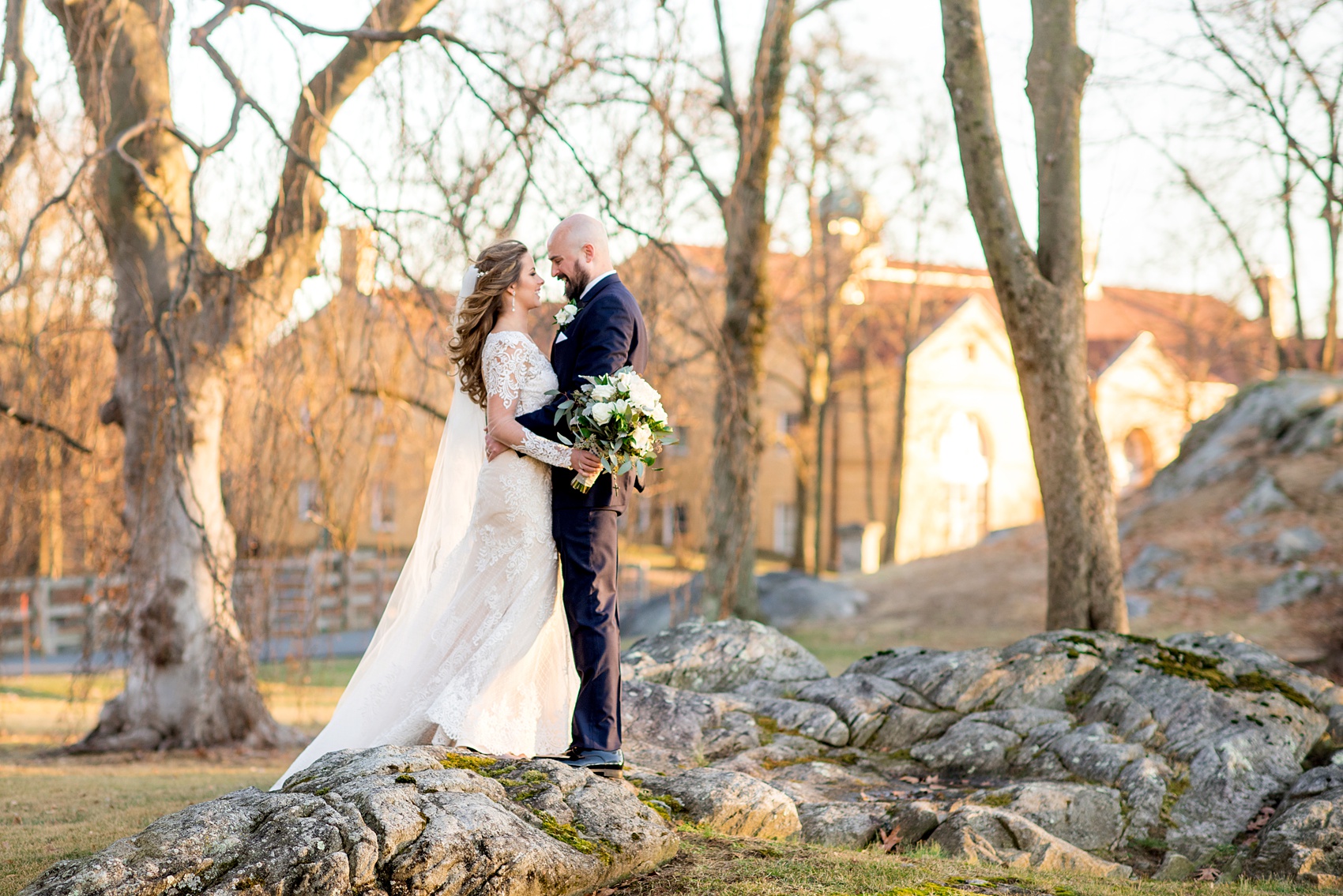 Wedding photos at Sleepy Hollow Country Club for a winter reception in January by Mikkel Paige Photography. A picture of the bride in her long sleeve, lace gown and groom in his navy blue tuxedo, looking at each other during their portraits.