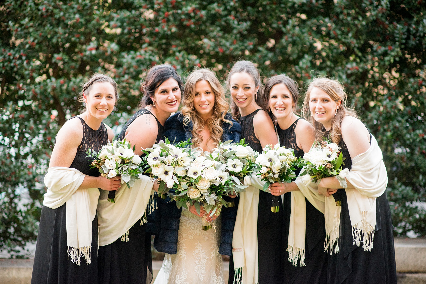 Wedding photos at Sleepy Hollow Country Club for a winter reception in January by Mikkel Paige Photography. The bridal party is pictured with white shawls and black lace gowns, surrounding the bride for her winter wedding. 
