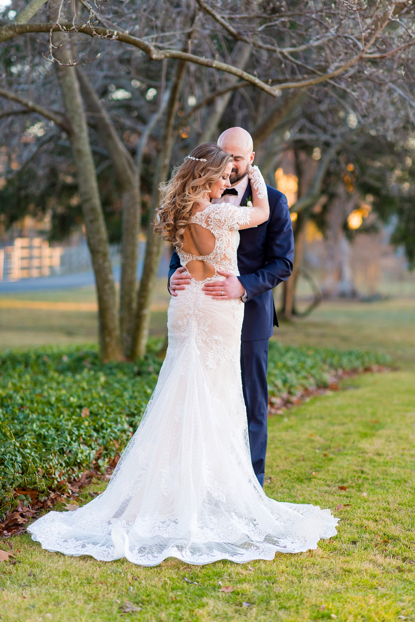 Wedding photos at Sleepy Hollow Country Club for a winter reception in January by Mikkel Paige Photography. A picture of the bride in her long sleeve, lace gown and groom in his navy blue tuxedo, during their portraits.