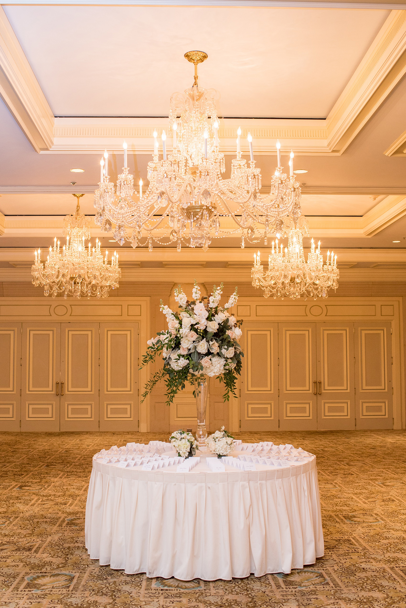Eau Palm Beach wedding photos by destination photographer, Mikkel Paige. This luxury West Palm Beach, Florida hotel is a beautiful location for a destination wedding. The escort cards were placed on a round table with a tall white flower centerpiece, under three grand chandeliers, leading into the ballroom. Click through to see more! #WestPalmBeach #EauPalmBeach #BeachWedding #FloridaWeddings #BeachBride