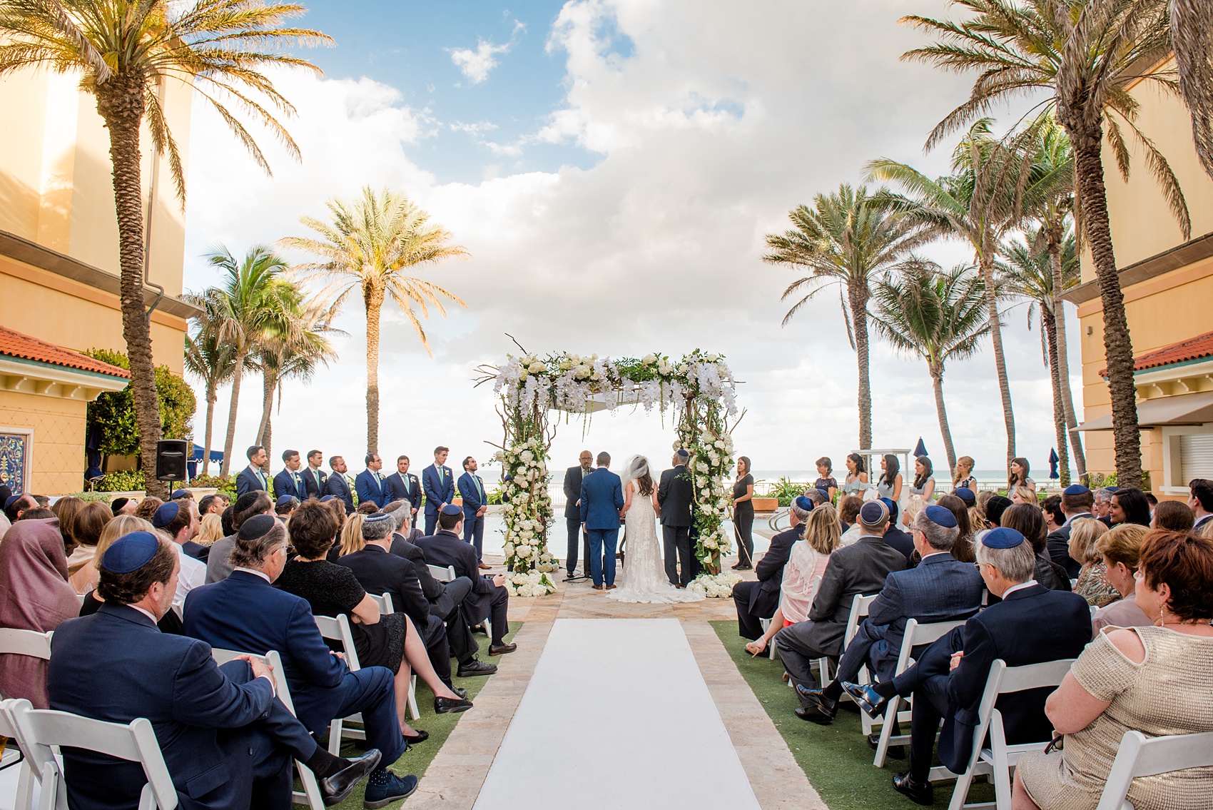 Eau Palm Beach wedding photos by destination photographer, Mikkel Paige. This luxury West Palm Beach, Florida hotel is a beautiful location for a destination wedding. The traditional Jewish ceremony took place outside under the palm trees, under a gorgeous chuppah. Click through to see more! #WestPalmBeach #EauPalmBeach #BeachWedding #FloridaWeddings #BeachBride #Jewishwedding #chuppah