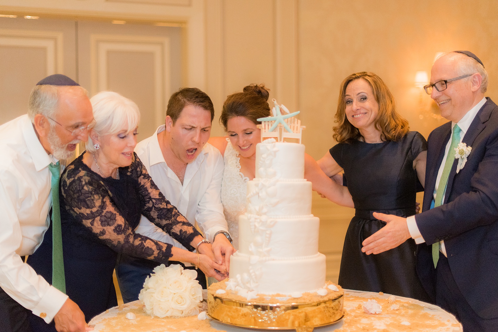 Eau Palm Beach wedding photos by destination photographer, Mikkel Paige. This luxury West Palm Beach, Florida hotel is a beautiful location for a destination wedding. The bride and groom cut their beach theme cake decorated with shells with their parents. Click through to see more! #WestPalmBeach #EauPalmBeach #BeachWedding #FloridaWeddings #BeachBride #CakeCutting #ShellCake