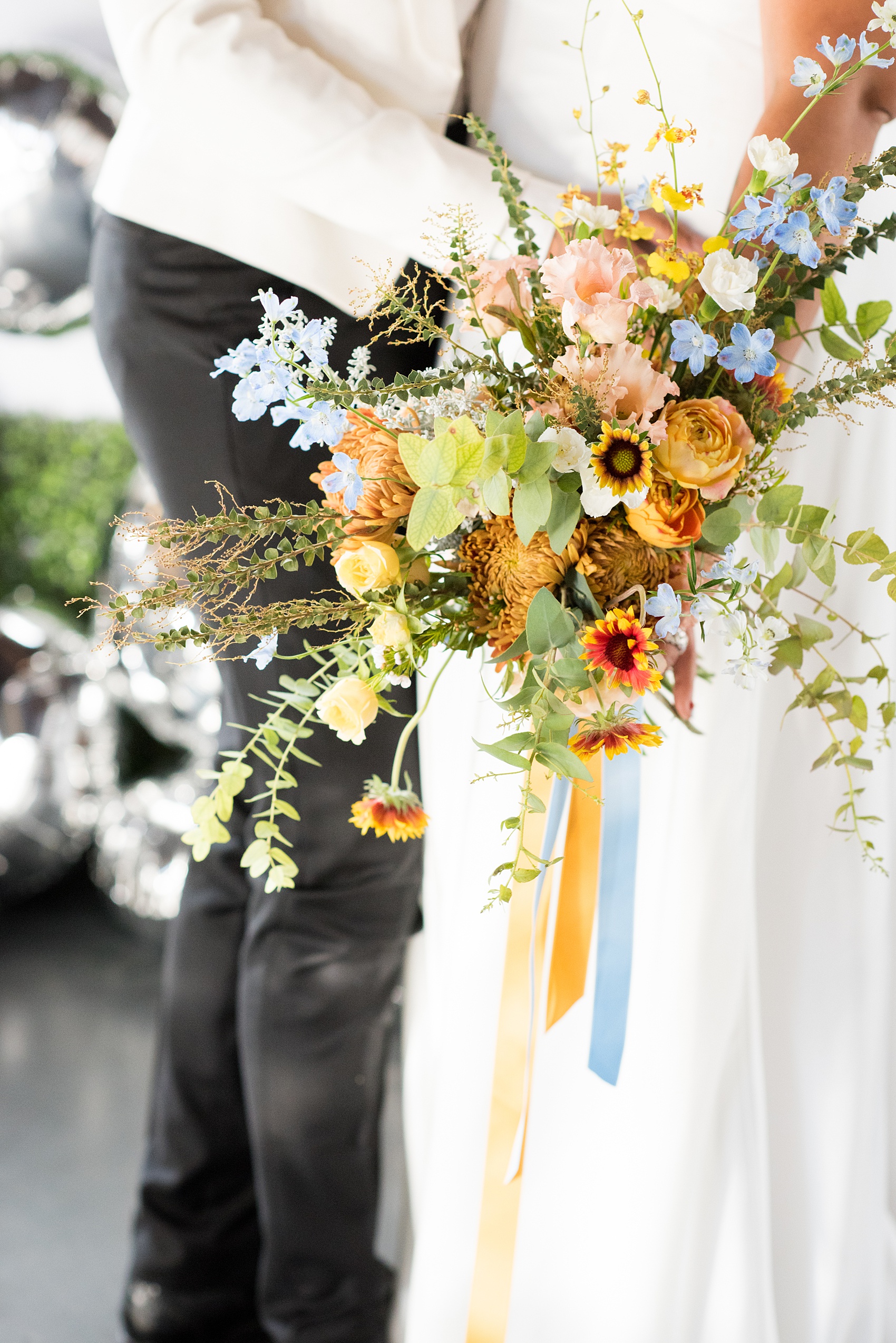 Mikkel Paige Photography photos of a wedding at the Green Building in Brooklyn, New York. This same sex, gay marriage styled shoot was created by Color Pop Events. This picture of the fall inspired bouquet shows it includes orange, yellow and blues, with garden roses, chrysanthemum, orchids and eucalyptus by Abby Tabak Studio.