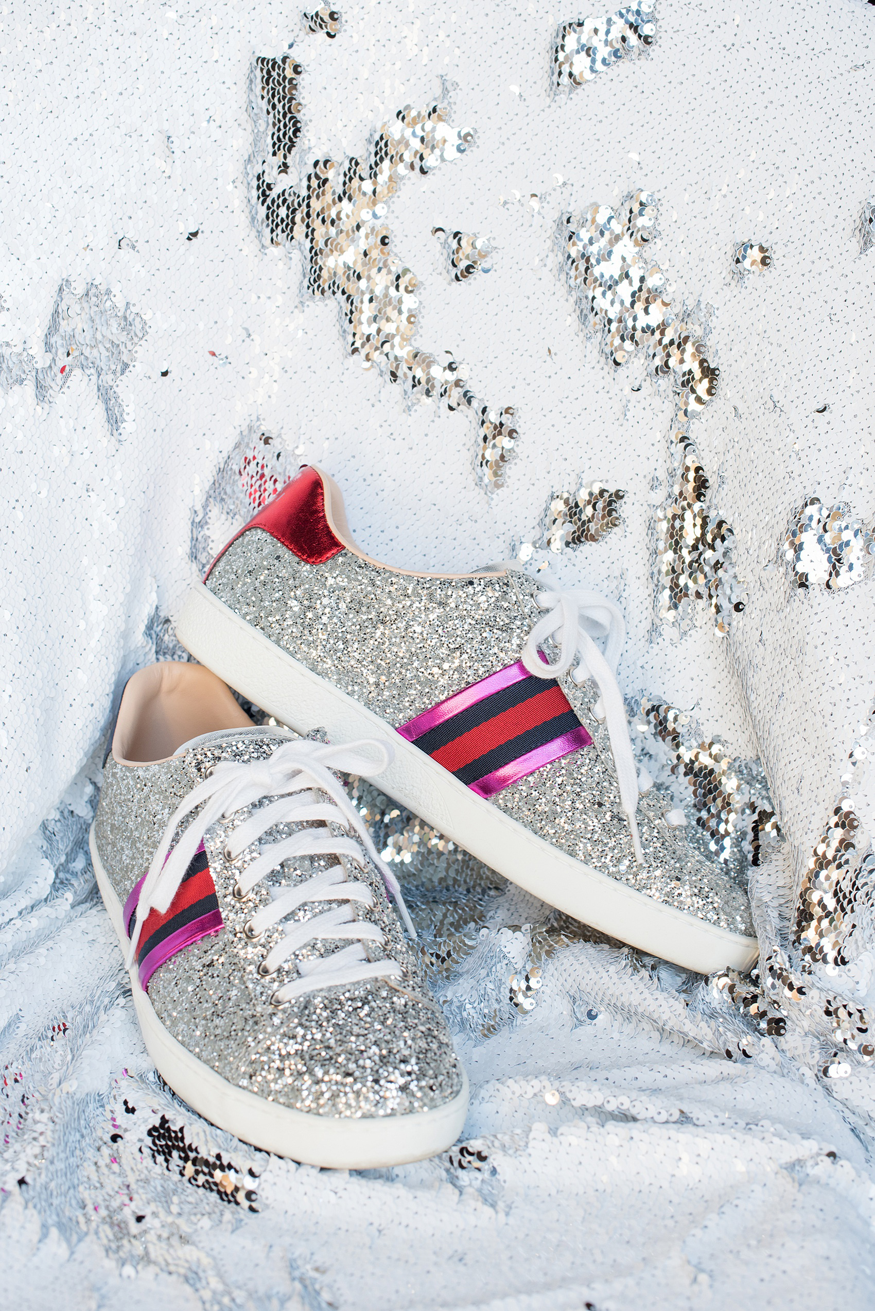 Mikkel Paige Photography photos of a wedding at the Green Building in Brooklyn, New York. This same sex, gay marriage styled shoot was created by Color Pop Events. This picture of the bride's silver glitter Gucci shoes shows the red and pink detail striping on the side of the comfortable footwear.