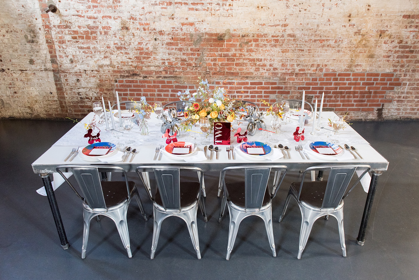Mikkel Paige Photography photos of a wedding at the Green Building in Brooklyn, New York. This same sex, gay marriage styled shoot was created by Color Pop Events. The urban dinner table was styled by Taylor and Hov, inspired by Jeff Koons and neo pop art. Flower centerpieces are by Abby Tabak Studio.