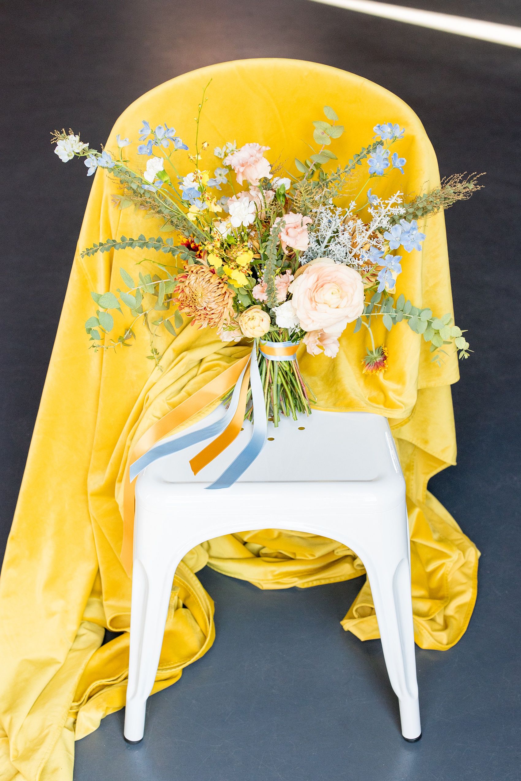 Mikkel Paige Photography photos of a wedding at the Green Building in Brooklyn, New York. This same sex, gay marriage styled shoot was created by Color Pop Events. This picture of the fall inspired bouquet shows it includes orange, yellow and blues, with garden roses, chrysanthemum, orchids and eucalyptus by Abby Tabak Studio.