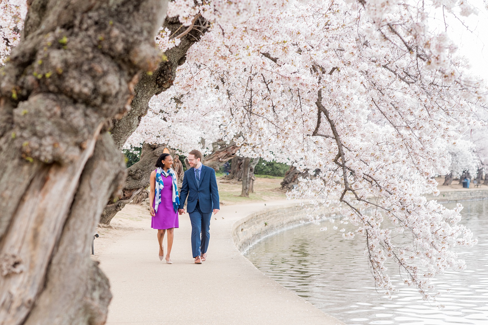 DC Cherry Blossoms Engagement Photos by Mikkel Paige Photography. Spring flowers around the Tidal Basin at the nation's Capitol with an interracial couple in colorful outfits. #DCCherryBlossoms #CherryBlossoms #EngagementPhotos #SpringEngagementPhotos #CherryBlossomsEngagementPhotos