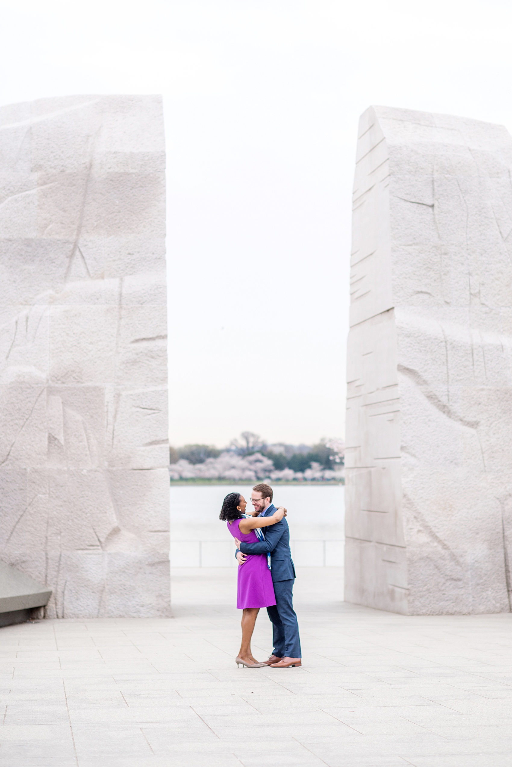 DC Cherry Blossoms Engagement Photos by Mikkel Paige Photography. Spring flowers at the Martin Luther King Jr. memorial at the nation's Capitol with an interracial couple in colorful outfits. #DCCherryBlossoms #CherryBlossoms #EngagementPhotos #SpringEngagementPhotos #CherryBlossomsEngagementPhotos