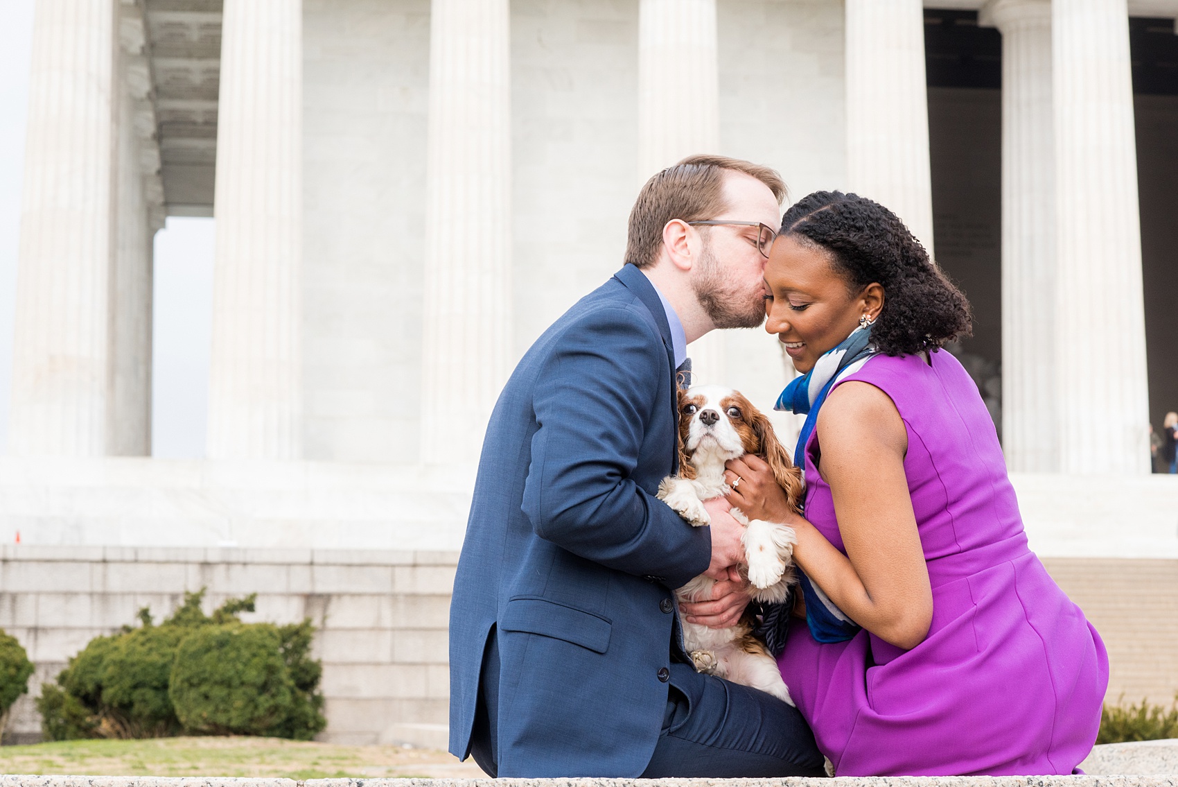 DC Cherry Blossoms Engagement Photos by Mikkel Paige Photography. Spring flowers around the MLK memorial and Tidal Basin at the nation's Capitol with a couple and their King Charles Spaniel dog. #DCCherryBlossoms #CherryBlossoms #EngagementPhotos #SpringEngagementPhotos #CherryBlossomsEngagementPhotos