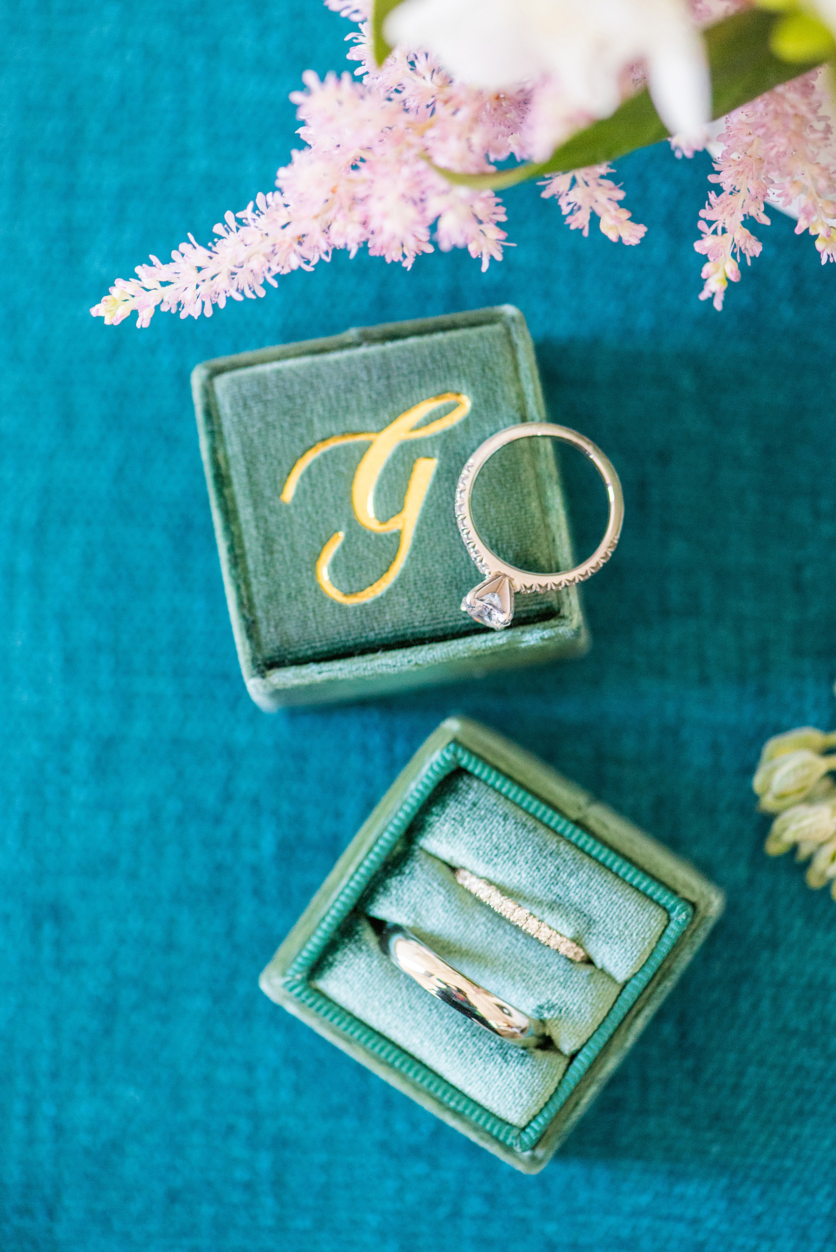 Saratoga Springs destination wedding photos by Mikkel Paige Photography. This detail picture shows the bride and groom's white gold wedding bands and diamond engagement ring with a "G" monogram green velvet Mrs. Box and her white and pink bouquet. #SaratogaSpringsNY #SaratogaSprings #mikkelpaige #NYwedding #destinationwedding #TheMrsBox #EngagementRing #RingBox