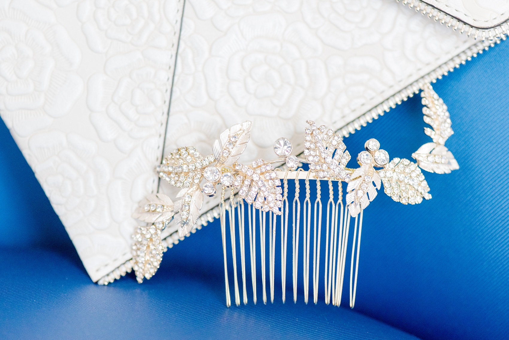 Saratoga Springs destination wedding photos by Mikkel Paige Photography. This detail picture shows the bride's rhinestone floral gold hair comb and white floral Rebecca Minkoff handbag with a zipper edge. #SaratogaSpringsNY #SaratogaSprings #mikkelpaige #NYwedding #destinationwedding #greenweddinginspiration #greenwedding #greenandgoldwedding #greenbridesmaids #bridalhandbag #bridalclutch #weddinghaircomb 