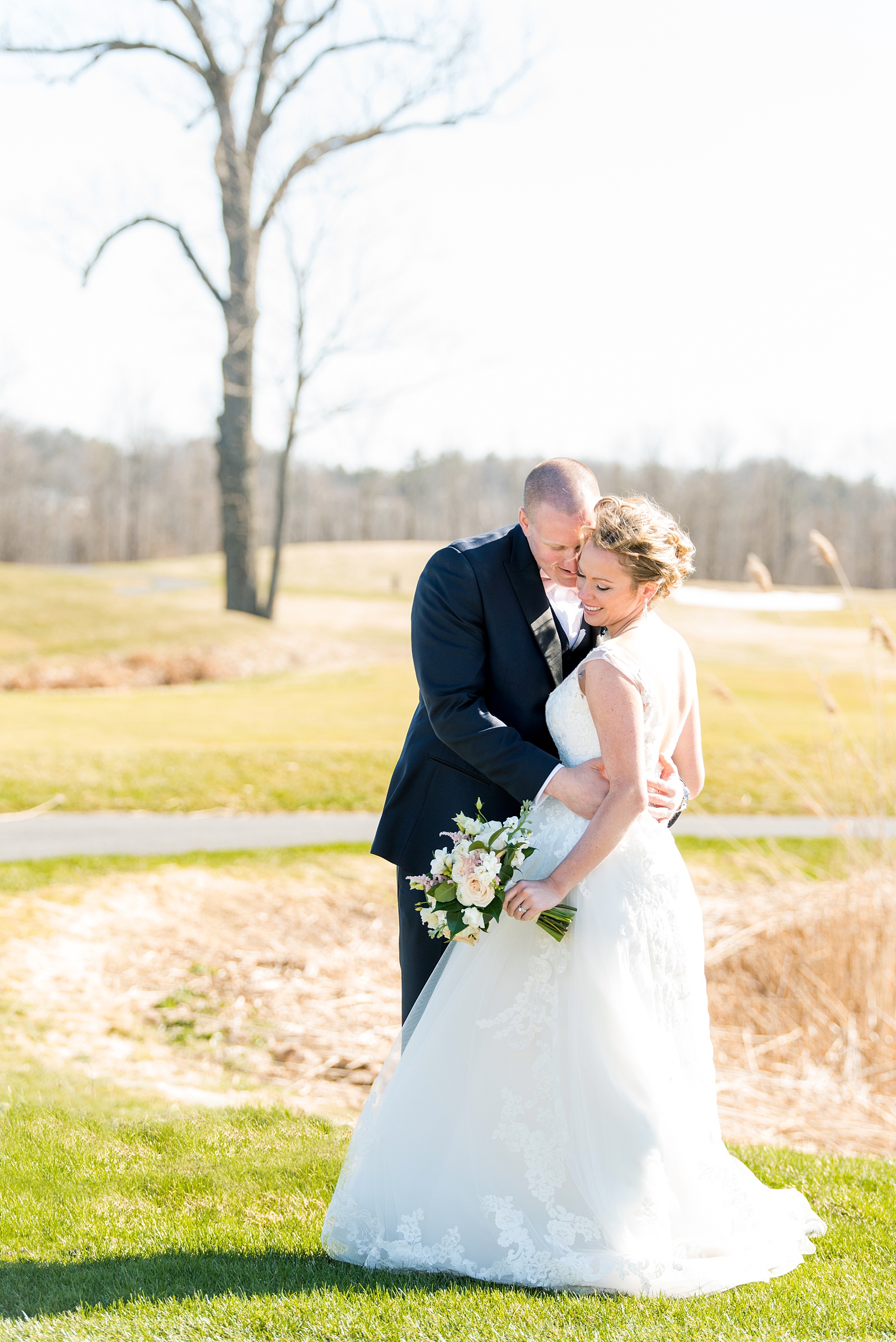 Saratoga Springs destination wedding photos by Mikkel Paige Photography. The bride and groom share a moment on the venue's green lawn surrounded by spring greenery for their reception held at Saratoga National Golf Club. #SaratogaSpringsNY #SaratogaSprings #mikkelpaige #NYwedding #destinationwedding 