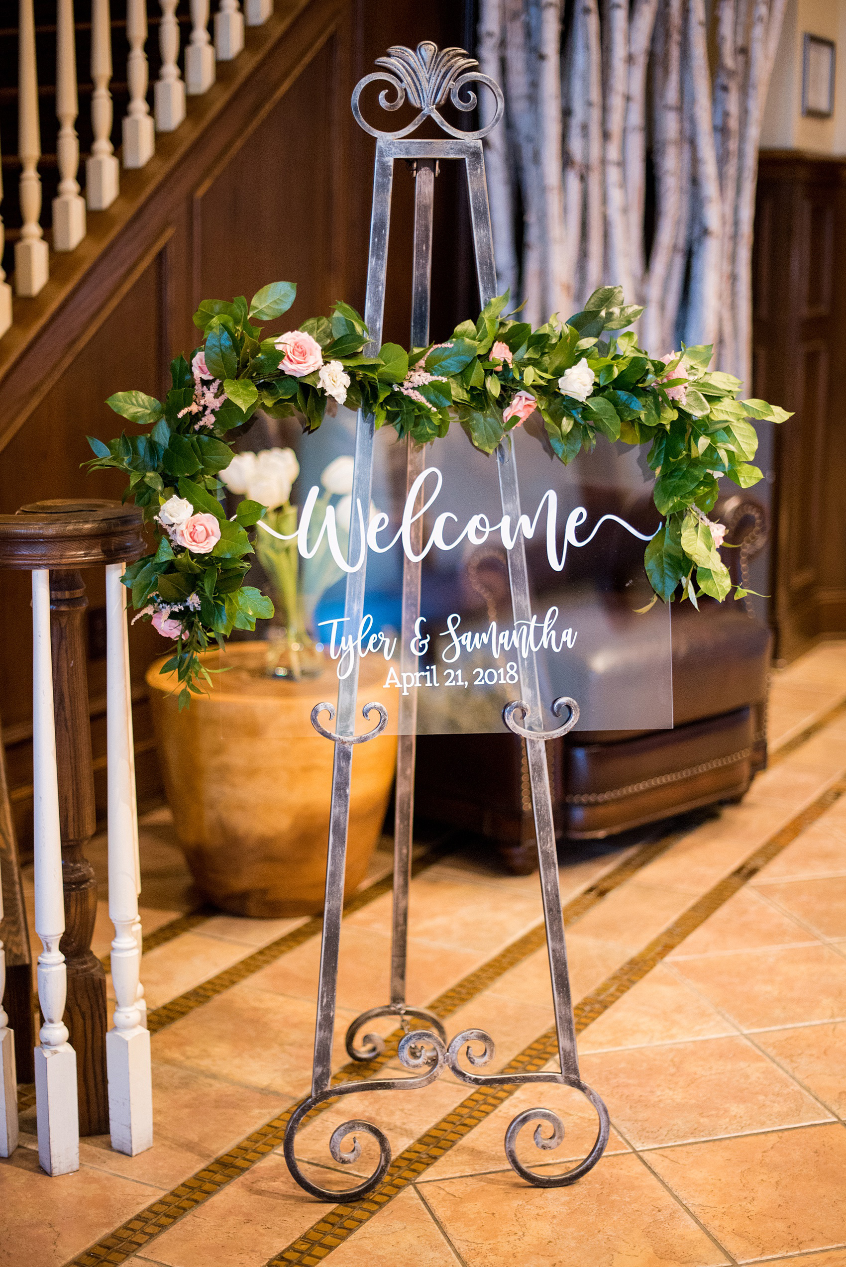 Saratoga Springs destination wedding photos by Mikkel Paige Photography. The spring event was held at Saratoga National Golf Club venue for a spring celebration. The bride and groom welcomed guests to the reception with a custom white and clear sign, decorated with flowers. #SaratogaSpringsNY #SaratogaSprings #mikkelpaige #NYwedding #destinationwedding #saratogaweddingvenue #golfcoursewedding #weddingsigns #customsignage #clearsigns #weddingwelcomesign