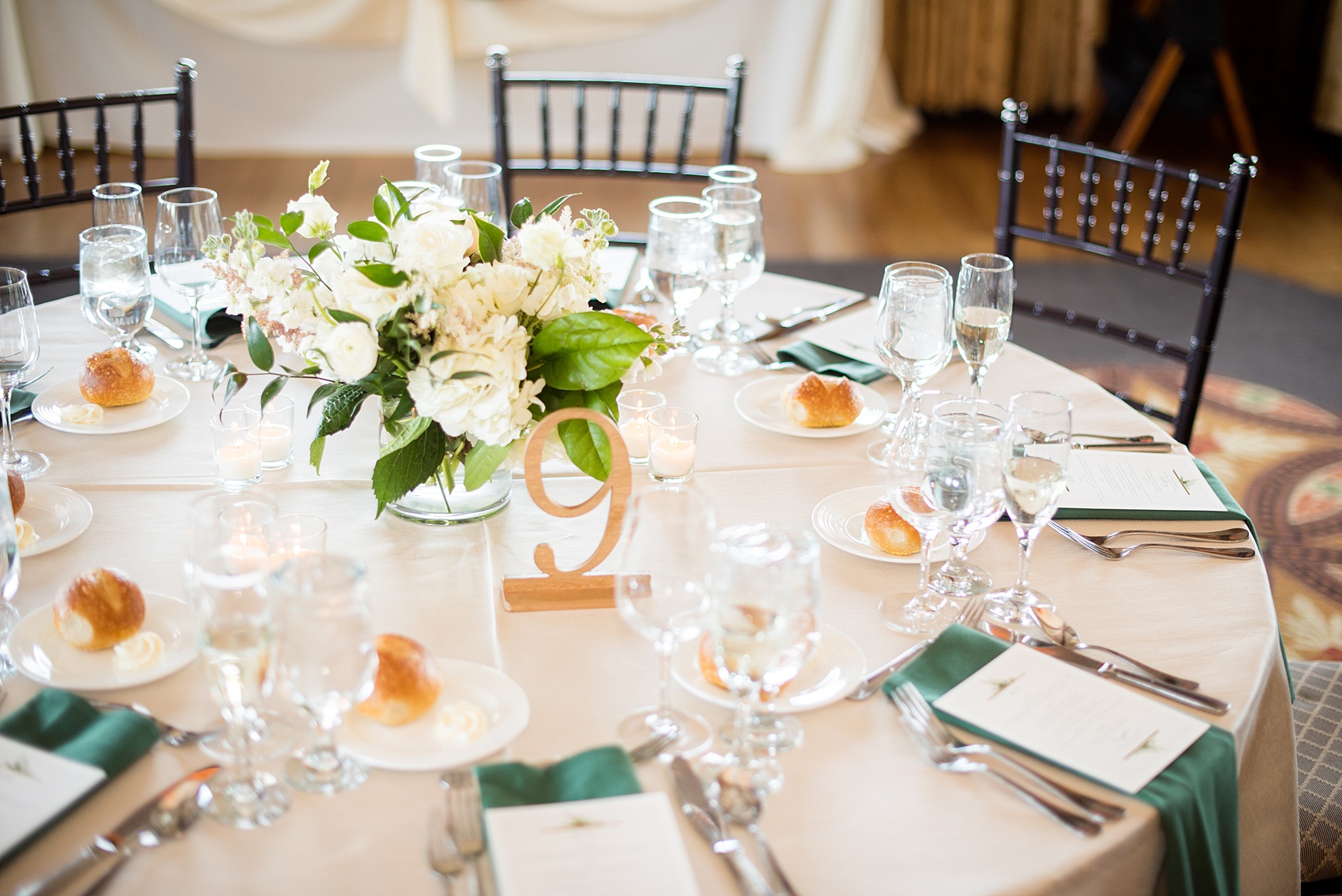 Saratoga Springs destination wedding photos by Mikkel Paige Photography. The spring event was held at Saratoga National Golf Club venue. The reception room was decorated with custom draping, and green and gold color palette elements including candlelight and wooden gold table numbers. #SaratogaSpringsNY #SaratogaSprings #mikkelpaige #NYwedding #destinationwedding #saratogaweddingvenue #golfcoursewedding #customdraping #springwedding