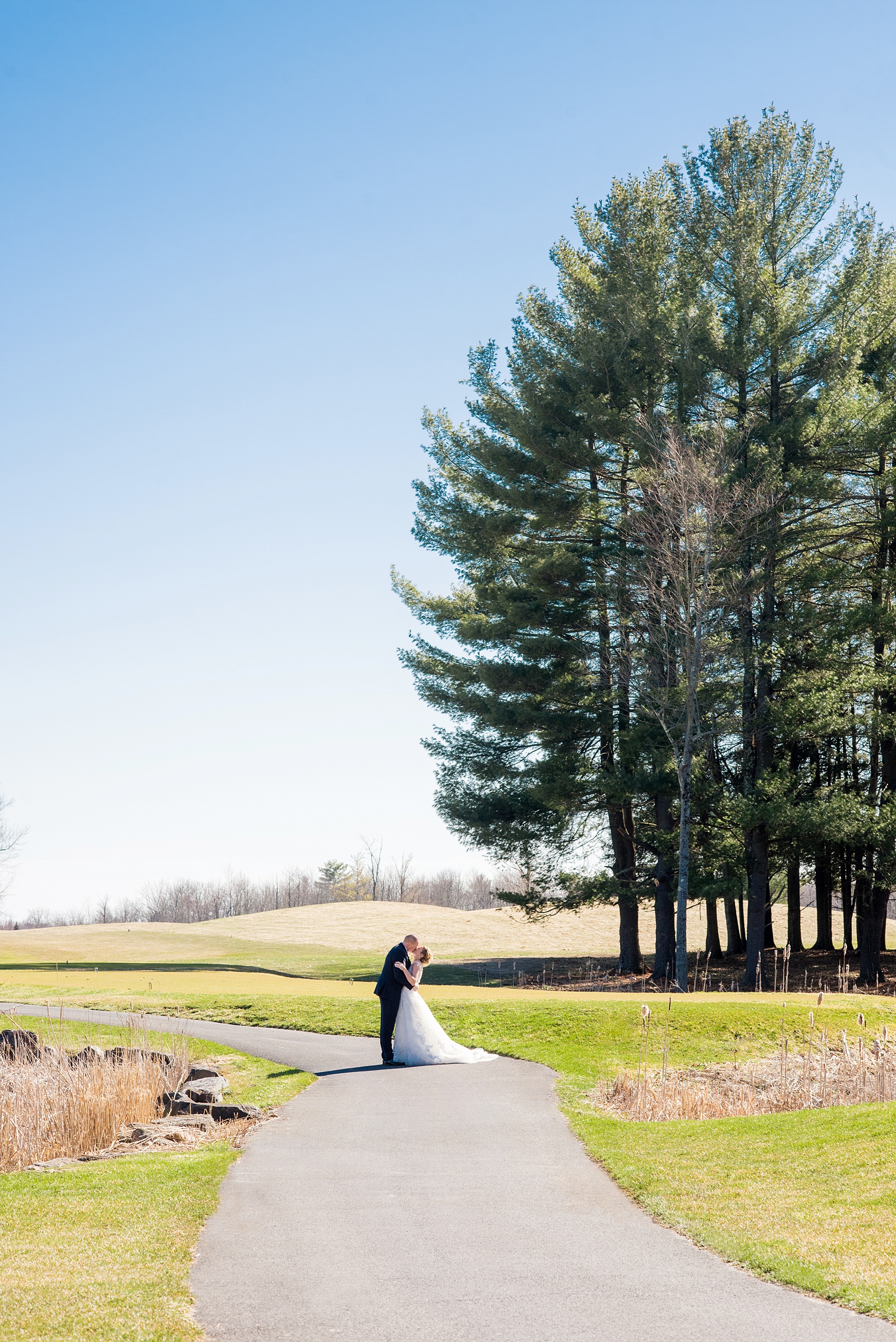 Photos from Saratoga Springs, New York by Mikkel Paige Photography. The bride and groom kiss on the golf course during their spring wedding. #SaratogaSprings #golfcoursewedding #SaratogaSpringsNY #SpringWedding 