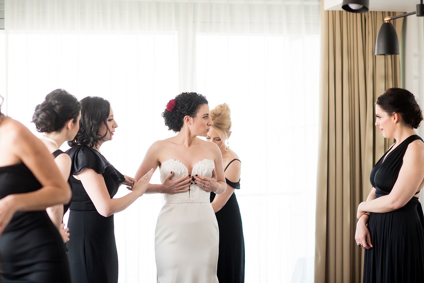 W Hoboken wedding photos by Mikkel Paige Photography. Picture of the bride getting into her Paloma Blanca, strapless pearl beaded wedding gown with her bridesmaids. #mikkelpaige #HobokenWedding #NewJerseyPhotographer #NewYorkCityPhotographer #NYCweddingphotographer #brideandgroomphotos #redpeonies #romanticwedding #springwedding #CityWedding